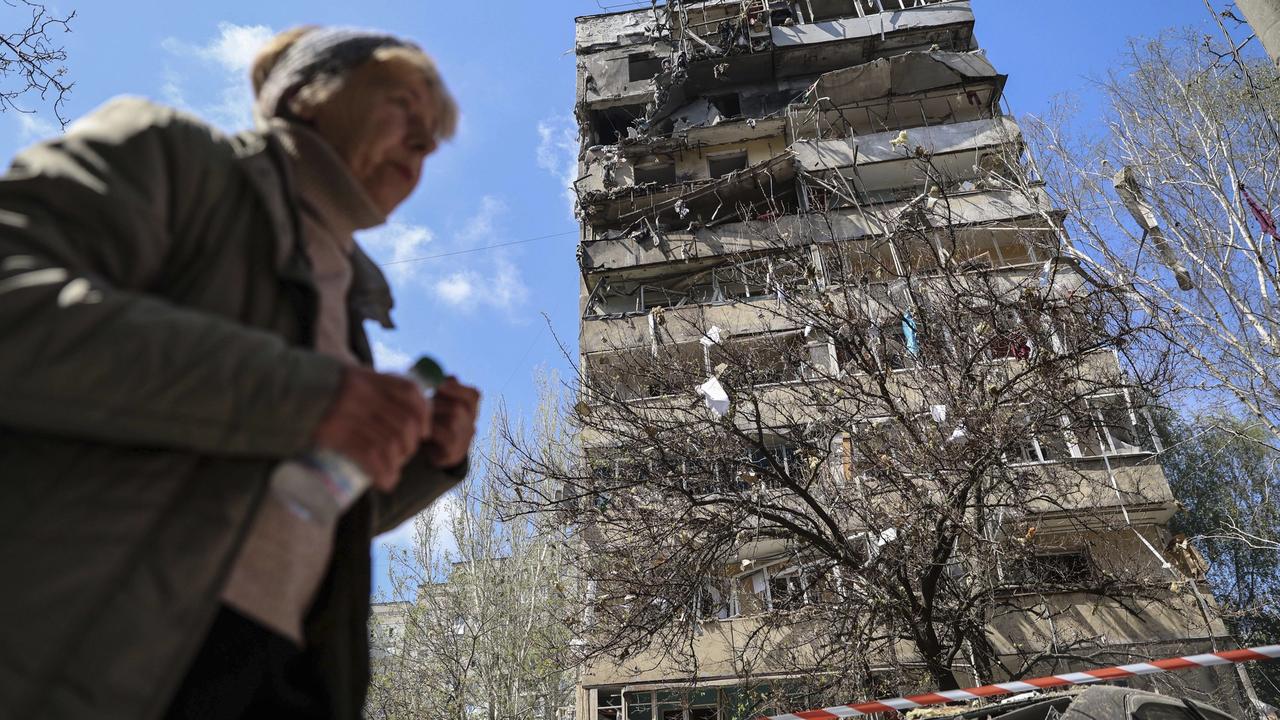 Na snímke žena kráča okolo viacposchodovej budovy, ktorú zasiahol útok ruskej armády na obytnú štvrť mesta Záporožie na juhovýchode Ukrajiny v utorok 22. apríla 2025.