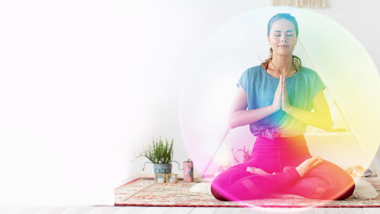 mindfulness, spirituality and healthy lifestyle concept - woman meditating in lotus pose at yoga studio over rainbow aura