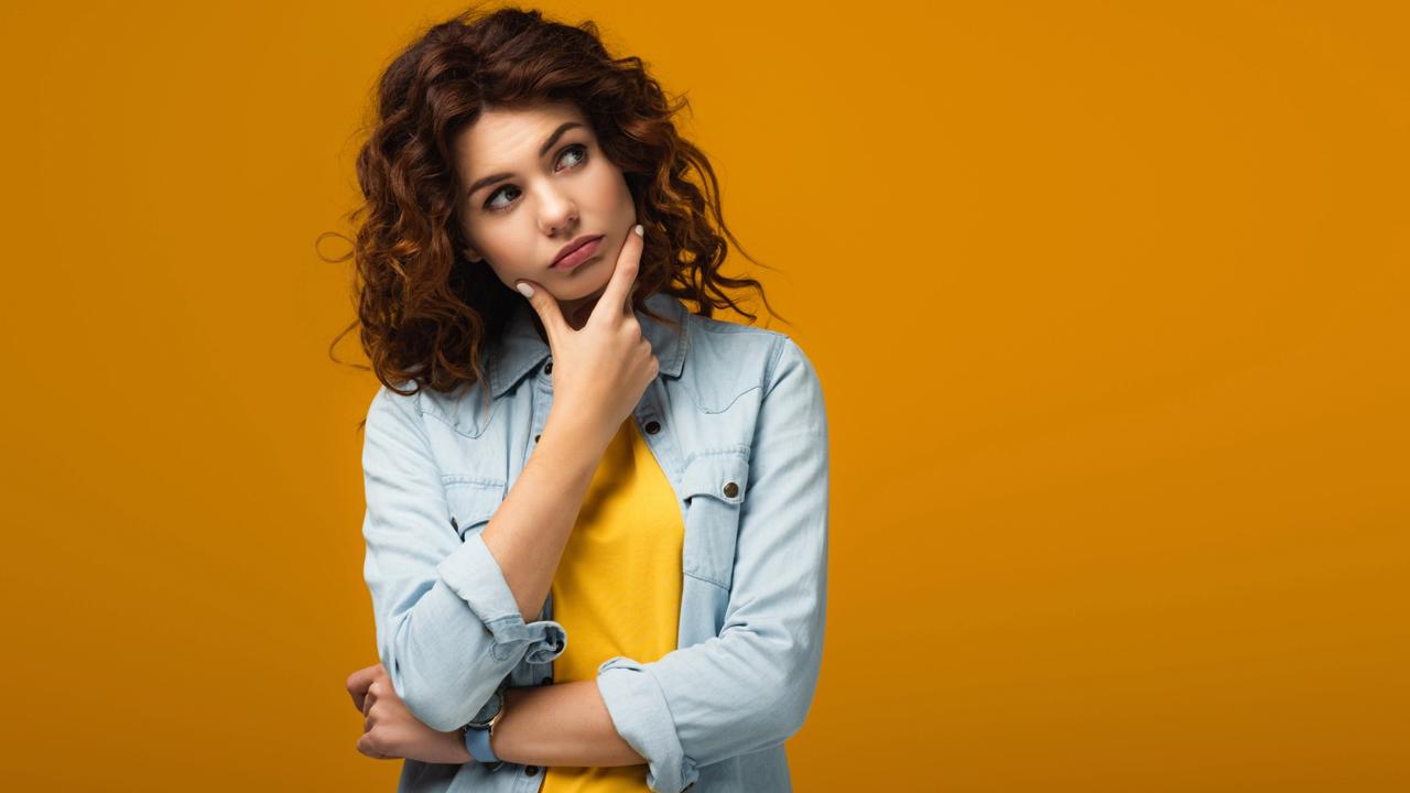 pensive redhead woman thinking while standing on orange