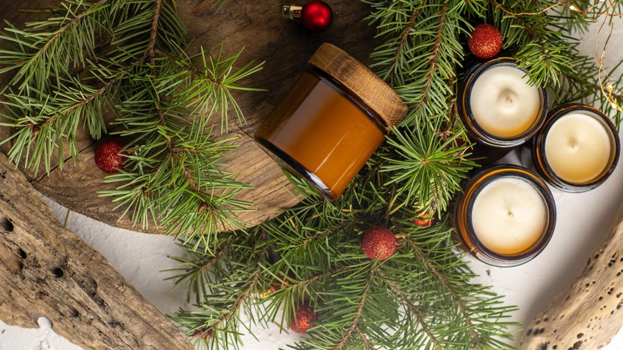 Soy candles burn in glass jars. Comfort at home. Candle in a brown jar. Scent and light. Scented handmade candle. Aroma therapy. Christmas tree and winter mood. Cozy decor. Festive garland decoration