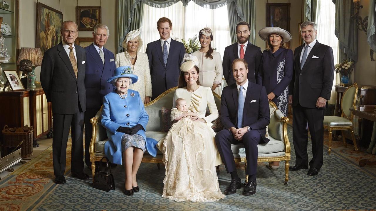 Vojvodkyňa Kate s malým Georgeom sedí medzi Williamom a kráľovnou Alžbetou. Horný rad zľava: Princ Philip, princ Charles a vojvodkyňa z Cornwallu, princ Harry, Pippa Middleton, James Middleton, Carole Middleton a Michael Middleton.