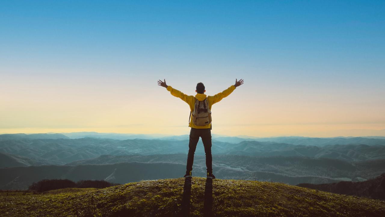 Hiker with arms up standing on the top of the mountain - Successful man enjoying triumph - Sport and success concept