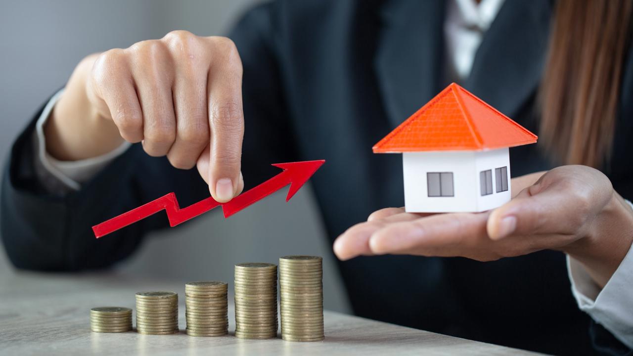 Businessman,Holding,Graph,Over,The,Increasing,House,Miniature,,Real,Estate