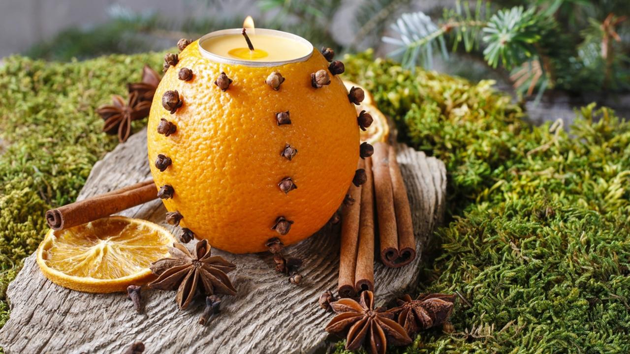 Orange pomander ball with candle, fir branches in the background