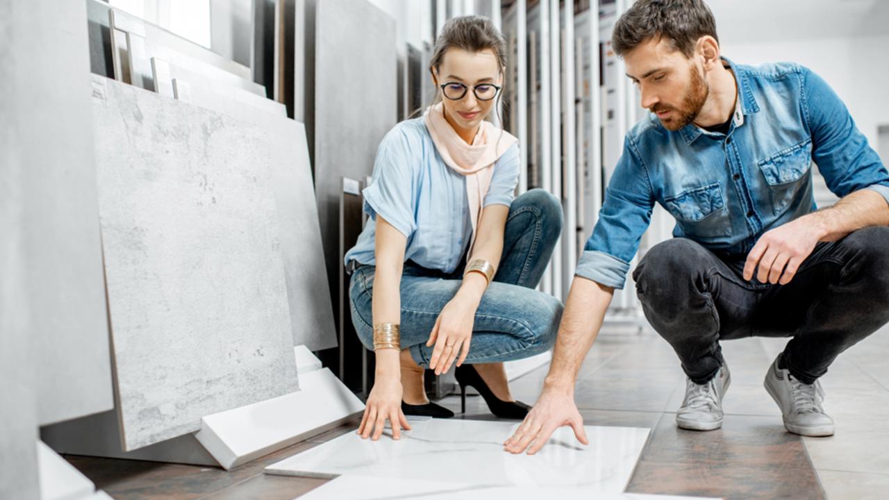 Beautiful young couple choosing big granite tiles for their house repairment in the building shop