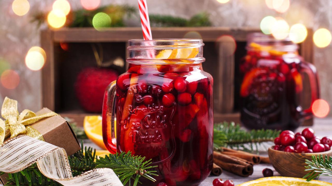 Cranberry and orange winter sangria near fireplace, Christmas decorated background. Copy space