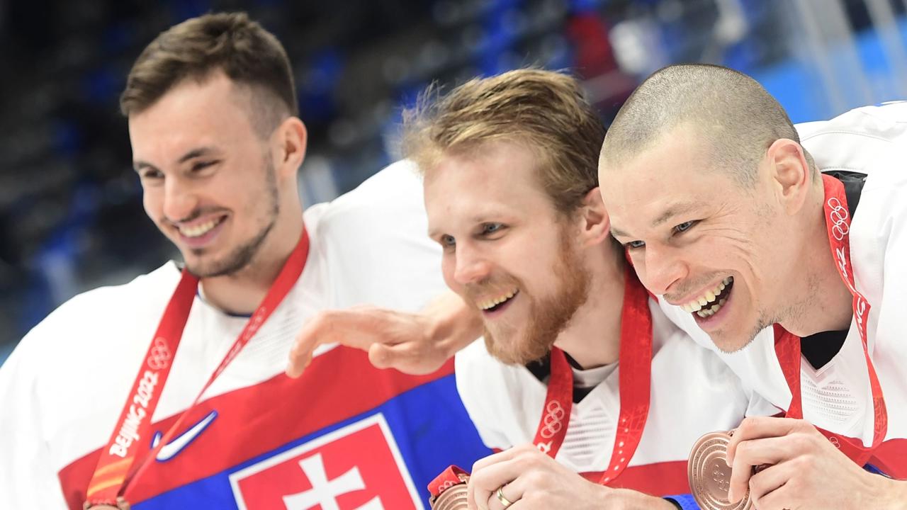 Slovenskí hráči sprava Marek Ďaloga, Michal Krištof a Matej Tomek oslavujú po zisku bronzu po zápase olympijského turnaja v hokeji mužov o bronz Slovensko - Švédsko na ZOH 2022 v Pekingu v sobotu 19. februára 2022.