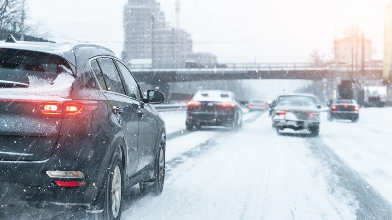 Scenic view snow covered city highway slippery road drive cars moving fast speed motion. Snowfall danger blizzard bad winter weather conditions. Urban cold snowy day snowstrom town background