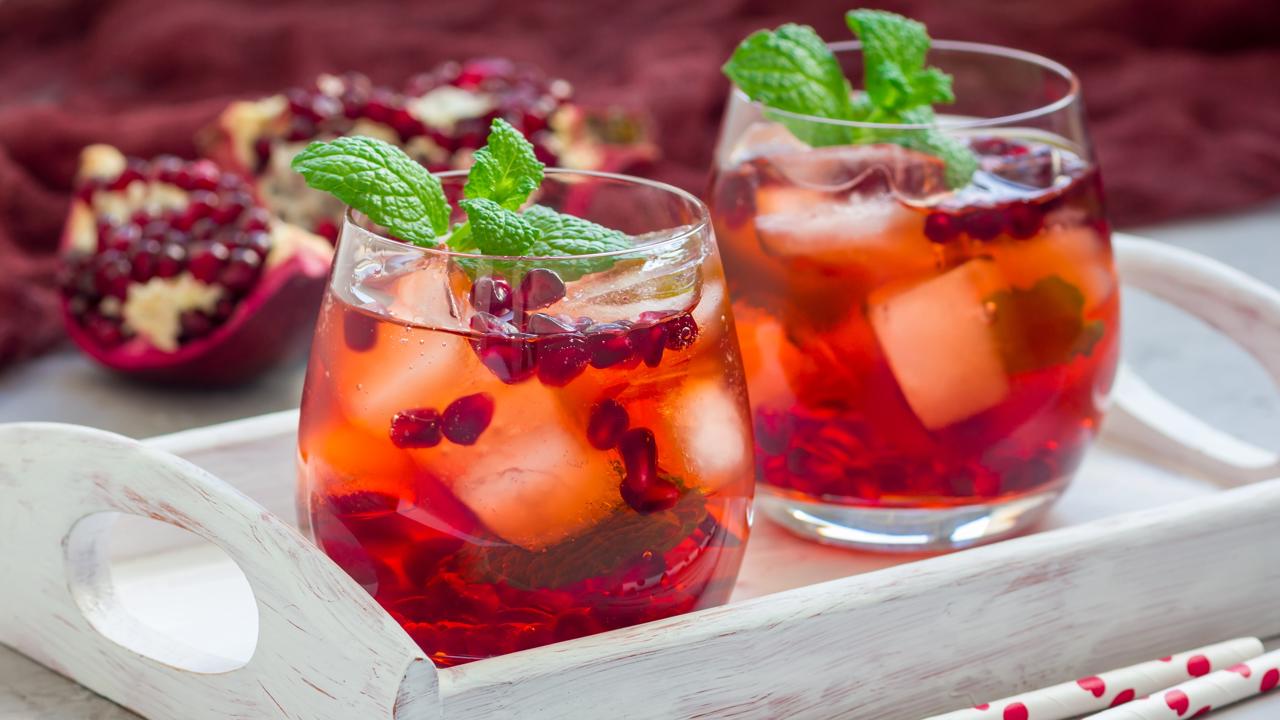 Mojito cocktail with pomegranate, mint, lemon juice and ice in glass, horizontal