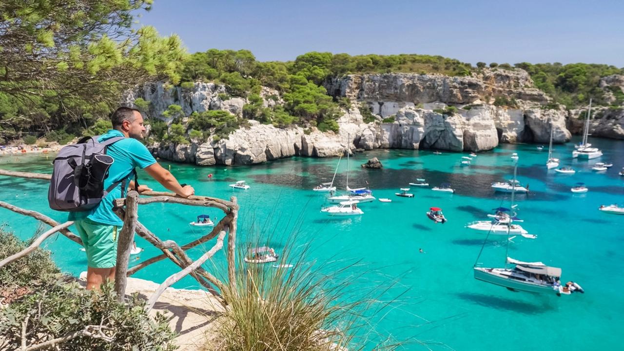Man admiring the panorama of Cala Macarella in Menorca, Spain