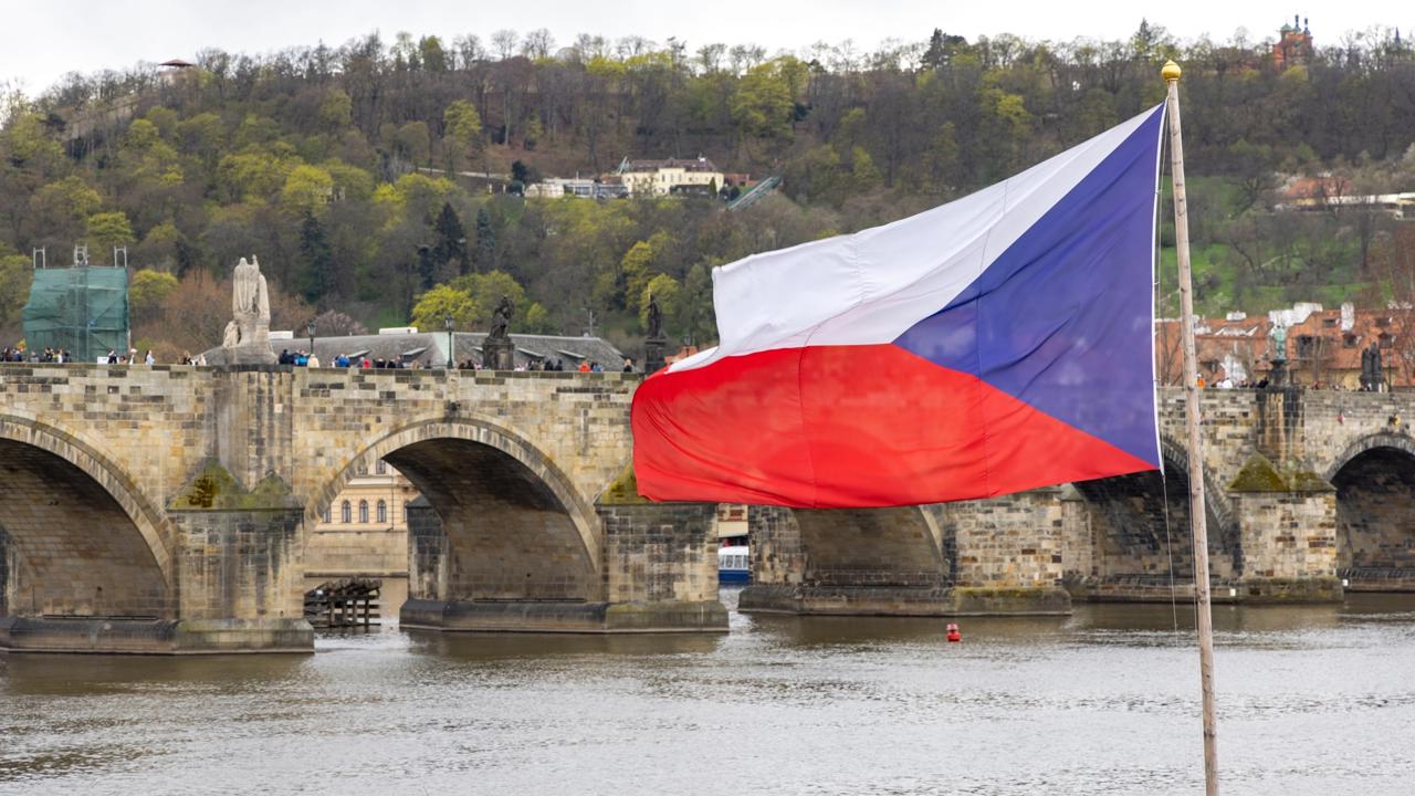 Česká vlajka s Karlovým mostom v pozadí.