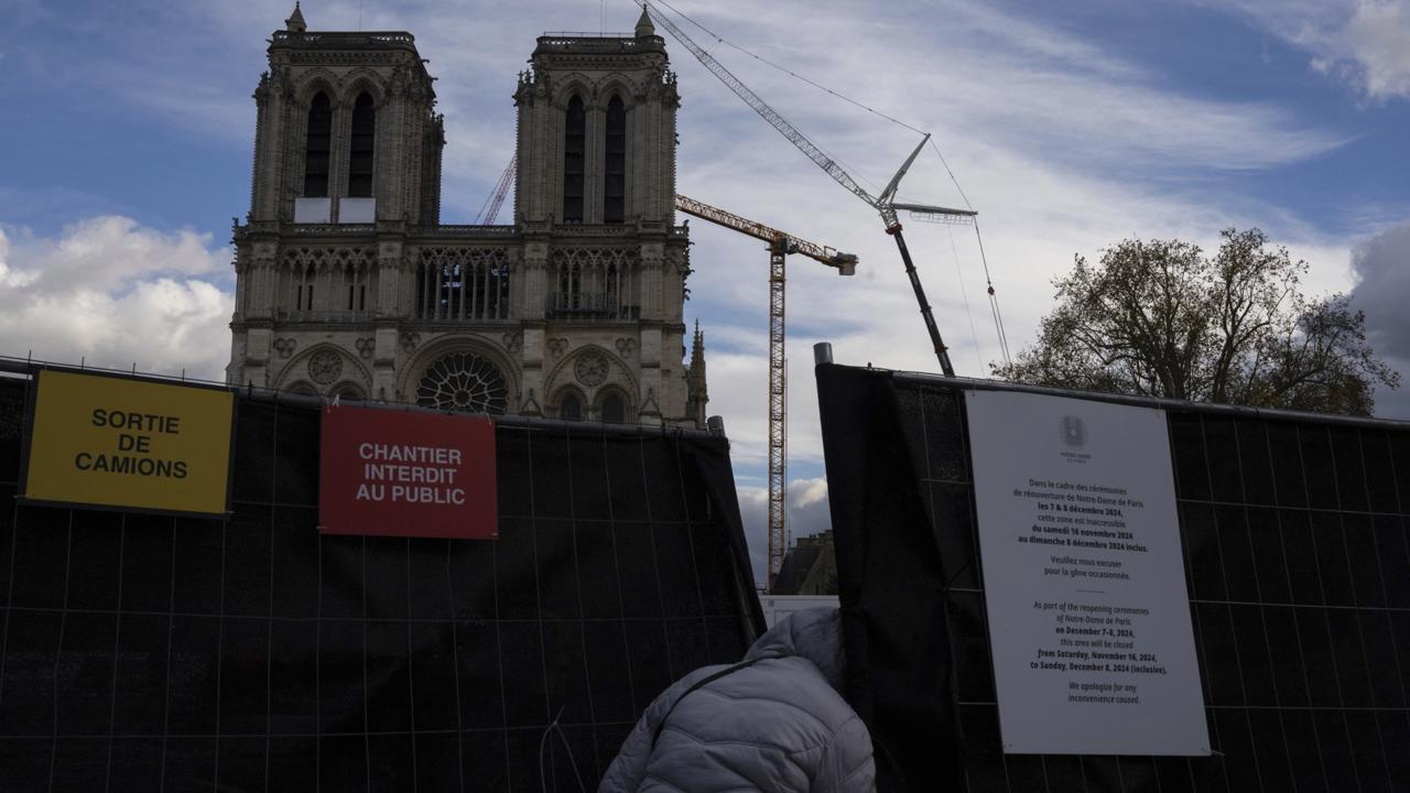 Na snímke chodec sa snaží nahliadnuť na nádvorie katedrály Notre Dame 20. novembra 2024 v Paríži. Znovuotvorenie rekonštruovanej parížskej katedrály je naplánované na 7. decembra 2024. FOTO TASR/AP