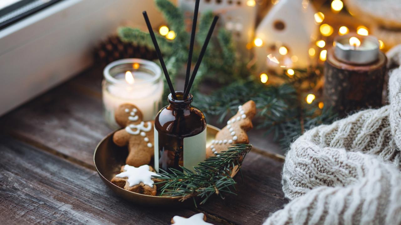 Christmas home aromatherapy. Aroma diffuser with pine extract, organic essential oil, cedar and spruce cone, cinnamon, anise, vanilla scent, candles, wooden table. Cozy atmosphere, winter inspiration