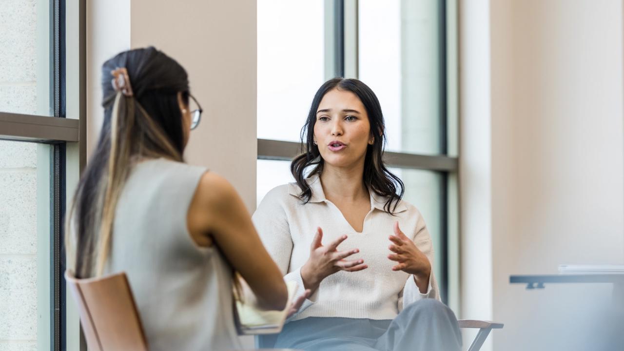 The young adult woman gestures as she details her experience during the interview with the unrecognizable businesswoman.