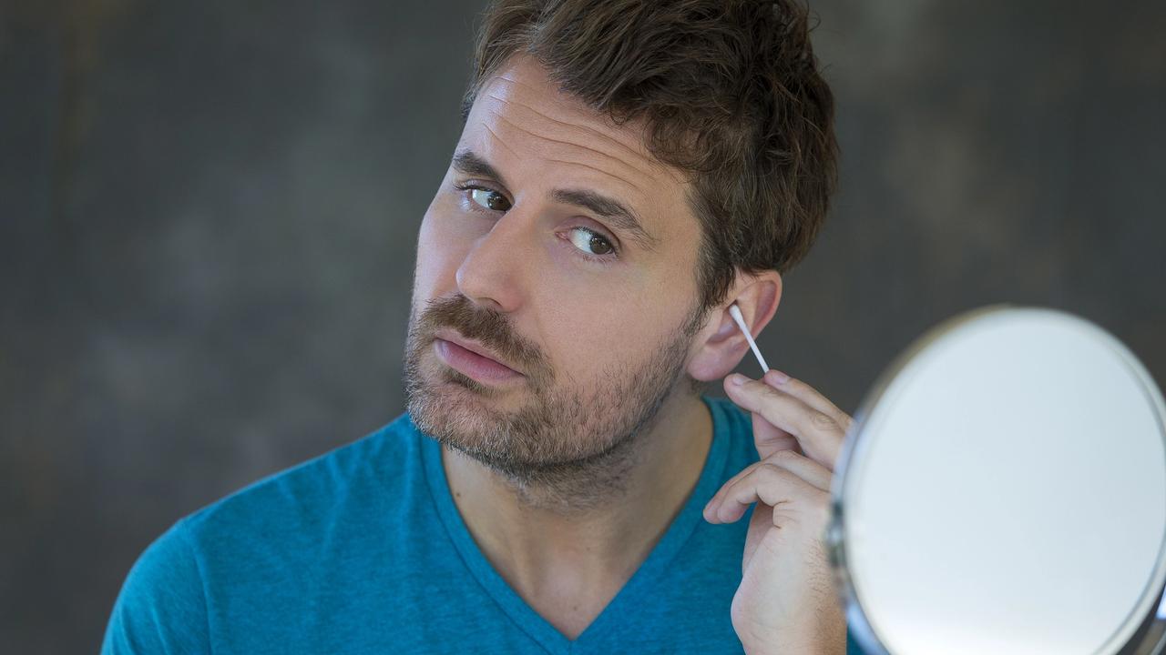 Mature man cleaning out his ears with a cotton bud.