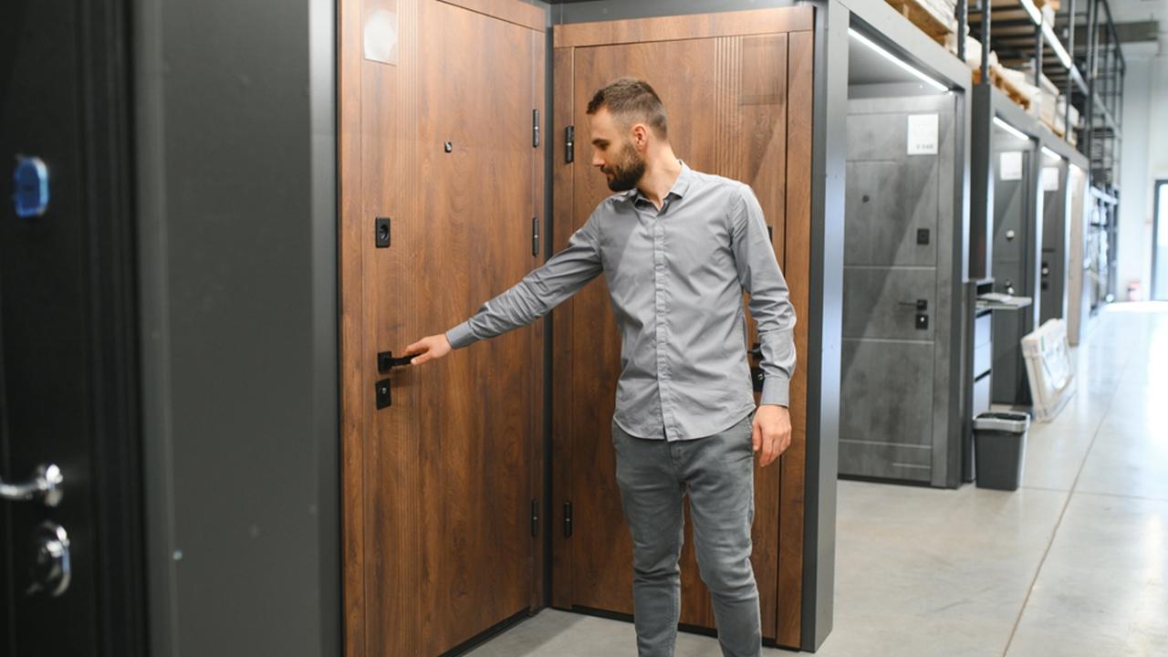 A young man chooses metal front door in the hardware store.