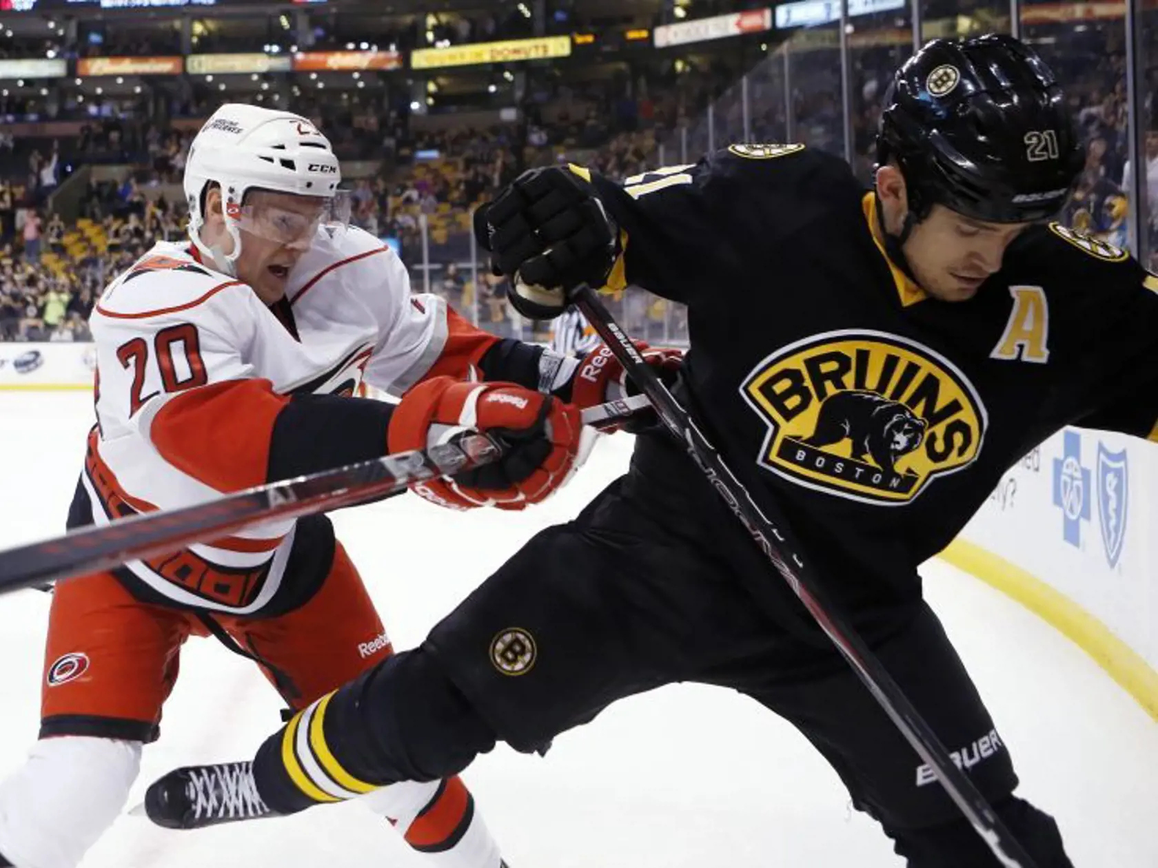 Riley Nash z Caroliny (v bielom) v súboji s Andrewom Ferencom z Bostonu.
