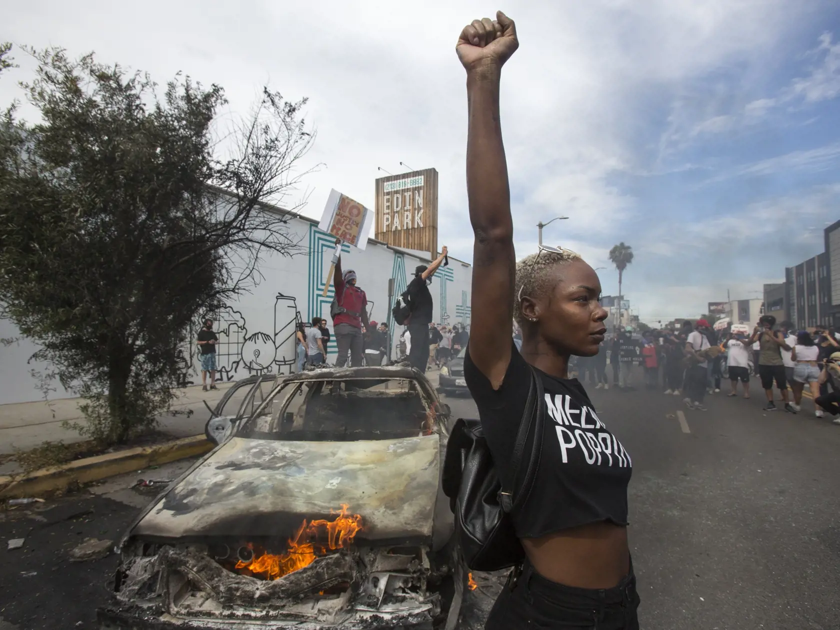 KK13 Los Angeles - Protestujúca pózuje vedľa zhoreného policajného auta počas pokračujúcich protestov proti zásahu polície sobotu 30. mája 2020 v Los Angeles. Afroameričana menom George Floyd zatkla polícia v pondelok večer. Videozáznam zhotovený okolostojacimi ľuďmi zachytáva spútaného muža ležiaceho na zemi. Jeden z policajtov v kľaku tlačil kolenom na Floydov krk. Zatknutý upozorňoval na bolesť a kričal, že nemôže dýchať. Krátko na to zomrel v nemocnici. FOTO TASR/AP
A protester poses for pho
