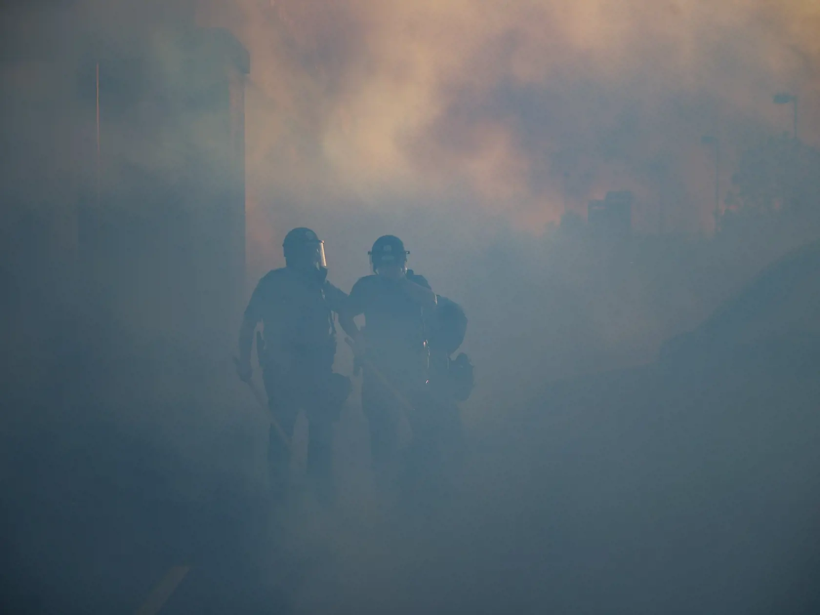 WA 23 St. Paul - Policajti kráčajú cez slzotvorný plyn počas pokračujúcich protestov v americkom meste St. Paul vo štvrtok 28. mája 2020. Ľudia protestujú proti policajnému zásahu v americkom meste Minneapolis už tretiu noc v rade. Afroameričana menom George Floyd zatkla polícia v pondelok večer. Videozáznam zhotovený okolostojacimi ľuďmi zachytáva spútaného muža ležiaceho na zemi. Jeden z policajtov v kľaku tlačil kolenom na Floydov krk. Zatknutý upozorňoval na bolesť a kričal, že nemôže dýchať