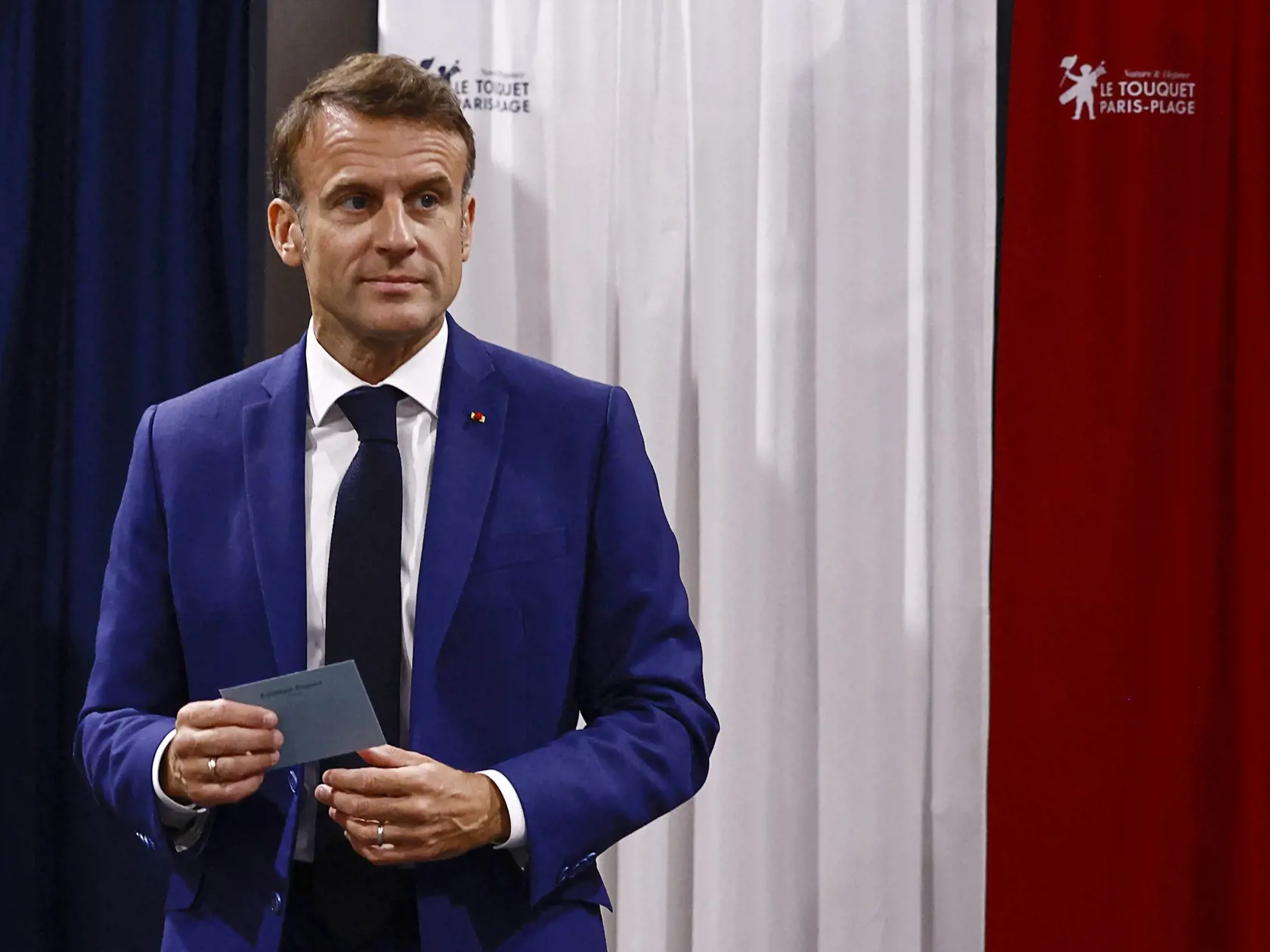 Francúzsky prezident Emmanuel Macron drží v ruke obálku s hlasovacím lístkom vo volebnej miestnosti v obci Le Touquet-Paris-Plage počas 1. kola predčasných parlamentných volieb vo Francúzsku v nedeľu 30. júna 2024. Predčasné voľby vyhlásil prezident Emmanuel Macron v reakcii na výsledky eurovolieb. Druhé kolo bude 7. júla.
