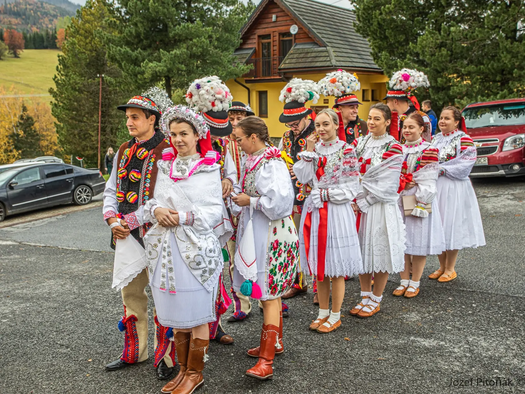 K snúbencom sa na nádvorí kostola pridali aj družbovia a družičky. Je neobyčajné, že pierko družbov vyzerá parádnejšie ako to, ktoré má na klobúku ženích.