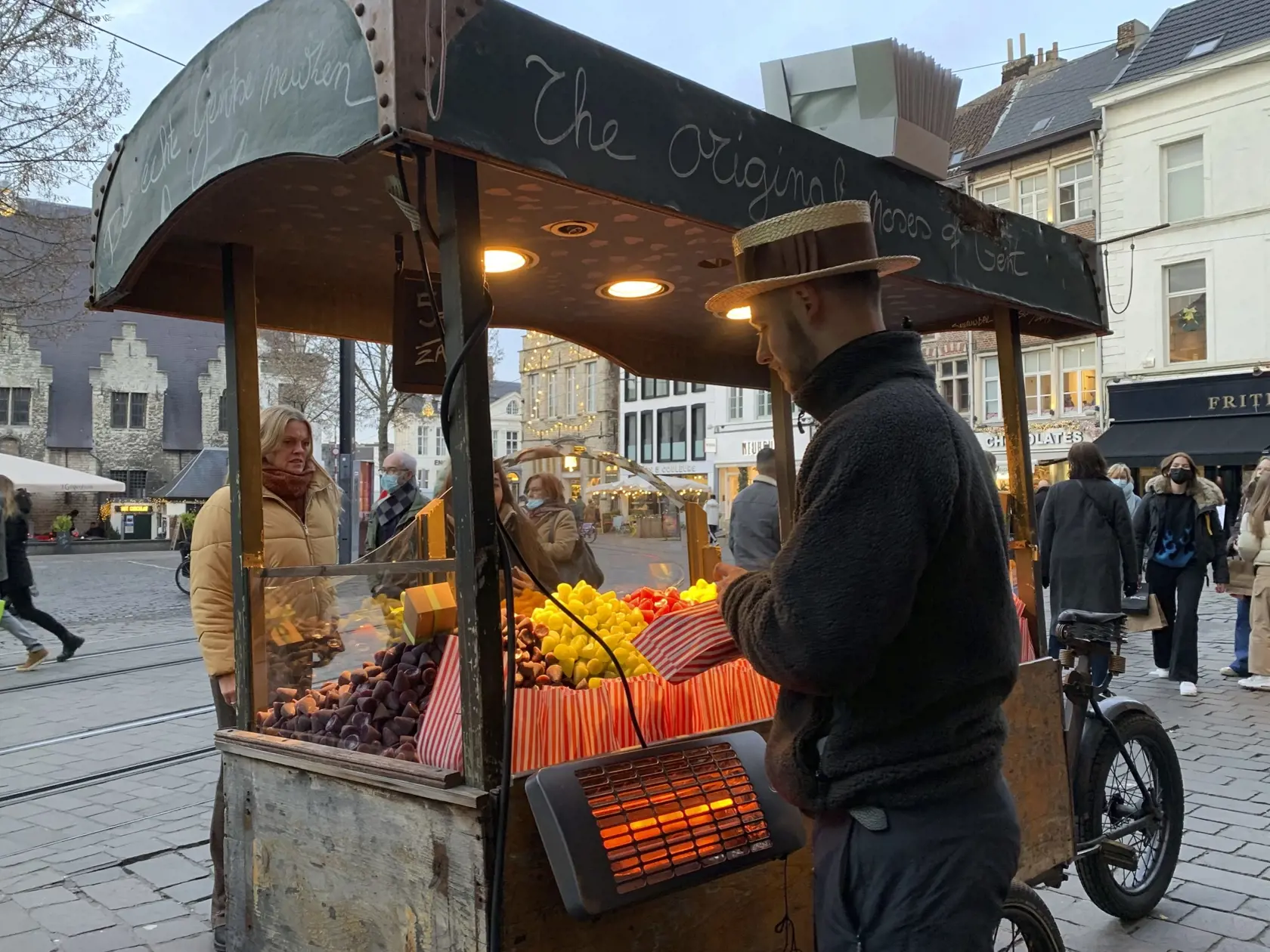 WA 40 Ghent - Pouličný predavač predáva sladkosti  v belgickom meste Ghent v stredu 22. decembra 2021. Belgická vláda v stredu oznámila, že koncertné sály, kiná a ďalšie zábavné podniky budú musieť byť od nedele zatvorené. Dôvodom je nárast počtu prípadov nákazy koronavírusovým variantom omikron v krajine, informovala agentúra AFP.  V Belgicku doteraz dostalo tretiu dávku vakcíny proti koronavírusu takmer 40 percent dospelej populácie. V krajine s 11 miliónmi obyvateľov dosiaľ ochoreniu COVID-19