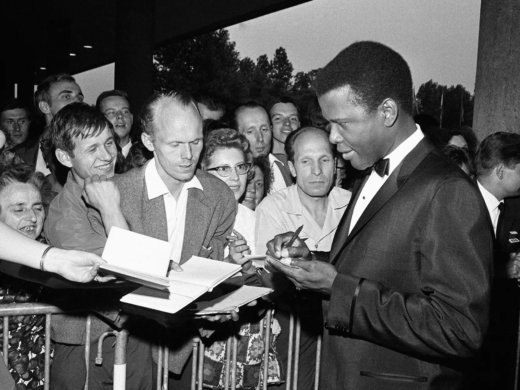 pk 10 archív Berlín - Na archívnej snímke z 26. júna 1964 americký herec Sidney Poitier dáva autogramy pred začiatkom 14. ročníka Medzinárodného filmového festivalu v Berlíne. Poitier, prvá veľká černošská filmová hviezda Hollywoodu, zomrel vo veku 94 rokov na Bahamách vo štvrtok 6. januára 2022. FOTO TASR/AP

FILE - Sidney Poitier signs autographs before the opening of the 14th International Film Festival at the West Berlin congress hall on June 26, 1964 in Berlin.  Poitier, the groundbreaking 