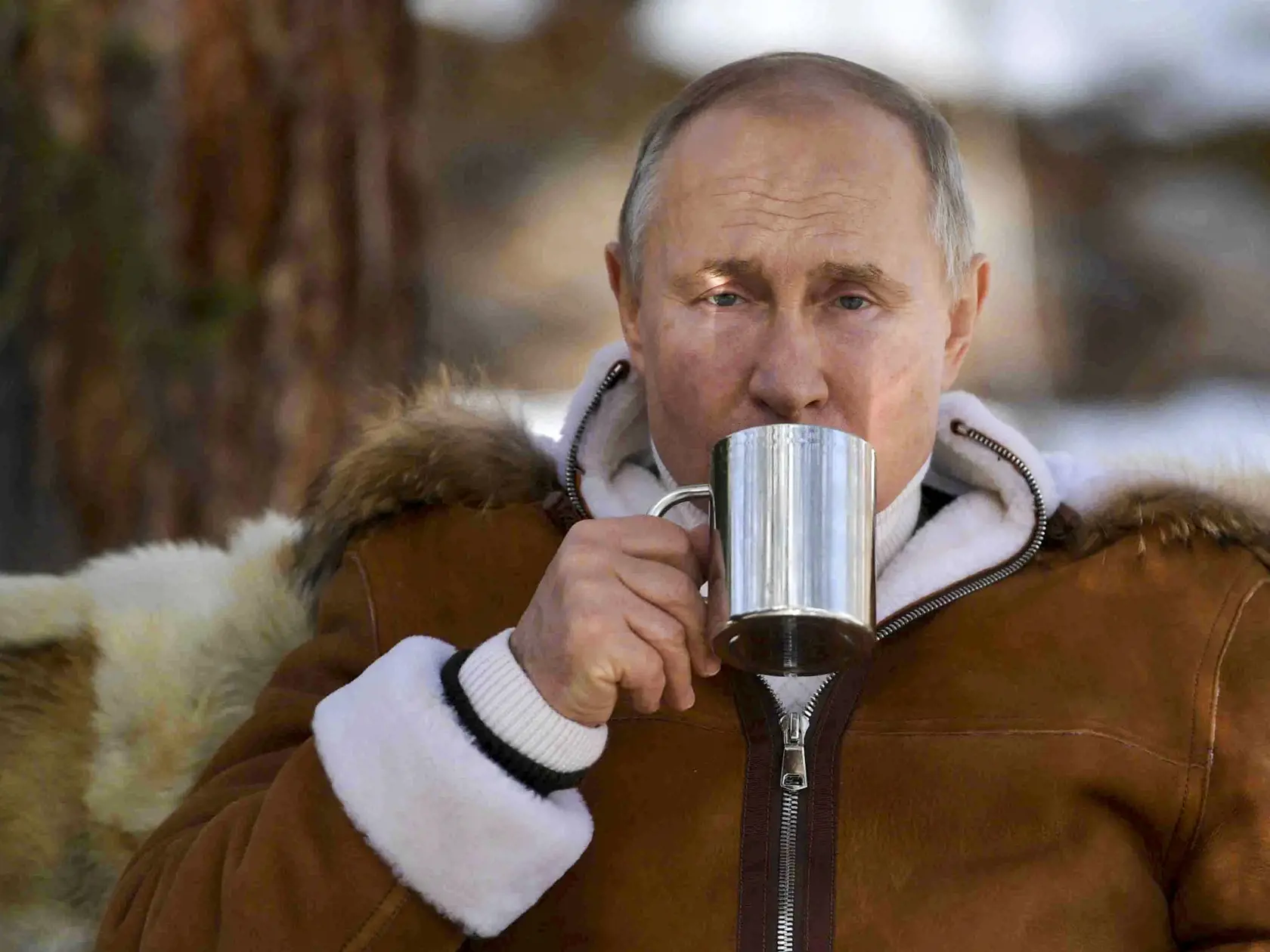 Ruský prezident Vladimir Putin pije zo šálky počas víkendovej návštevy tajgy na Sibíri 21. marca 2021.