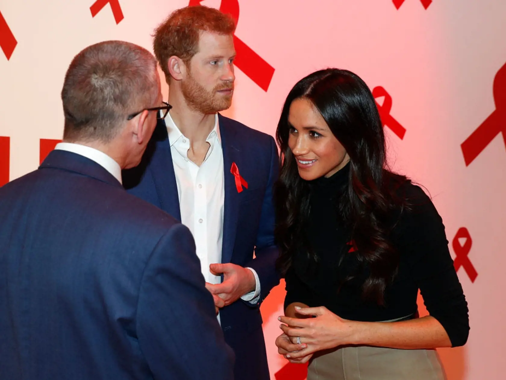 DENNIS  NOTTINGHAM, ENGLAND - DECEMBER 01:  Prince Harry (C) and his fiancee US actress Meghan Markle (L) meet with a representative of a charity working around HIV/AIDS at the Terrence Higgins Trust World AIDS Day charity fair at Nottingham Contemporary, as part of their first set of official public engagements together, on December 1, 2017 in Nottingham, England.  Prince Harry and Meghan Markle announced their engagement on Monday 27th November 2017 and will marry at St George's Chapel, Windso