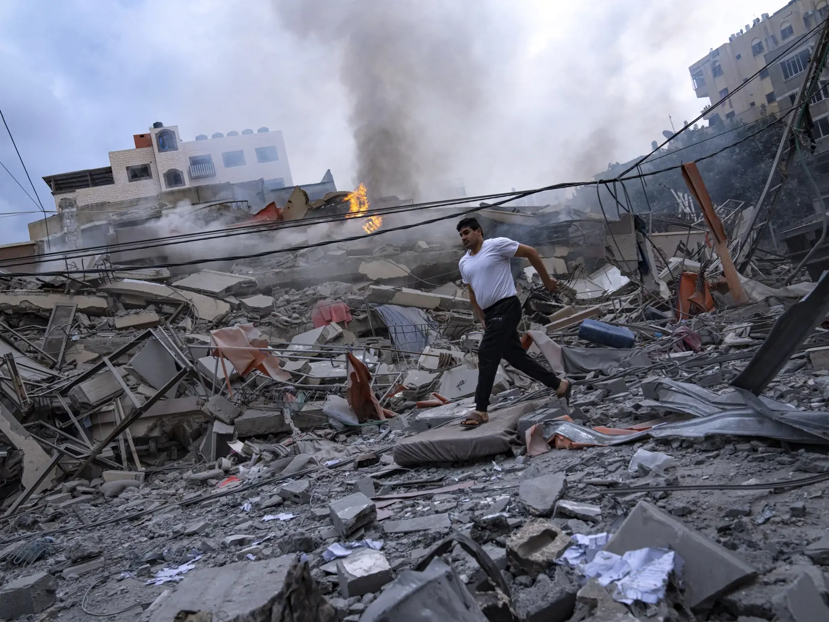 KK20 Gaza - Palestínčania kráčajú medzi ruinami po izraelských leteckých útokoch, ktoré zrovnali so zemou časť štvrte v meste Gaza, utorok 10. októbra 2023. V sobotu vpadli komandá útočníkov palestínskeho hnutia Hamas z pásma Gazy na územie Izraela, kde bezhlavo zabíjali civilistov i príslušníkov ozbrojených zložiek a brali rukojemníkov vrátane žien, detí a seniorov. Ich vpád sprevádzalo masívne ostreľovanie územia Izraela. Útok Hamasu si na území Izraela vyžiadal najmenej 900 obetí na životoch.