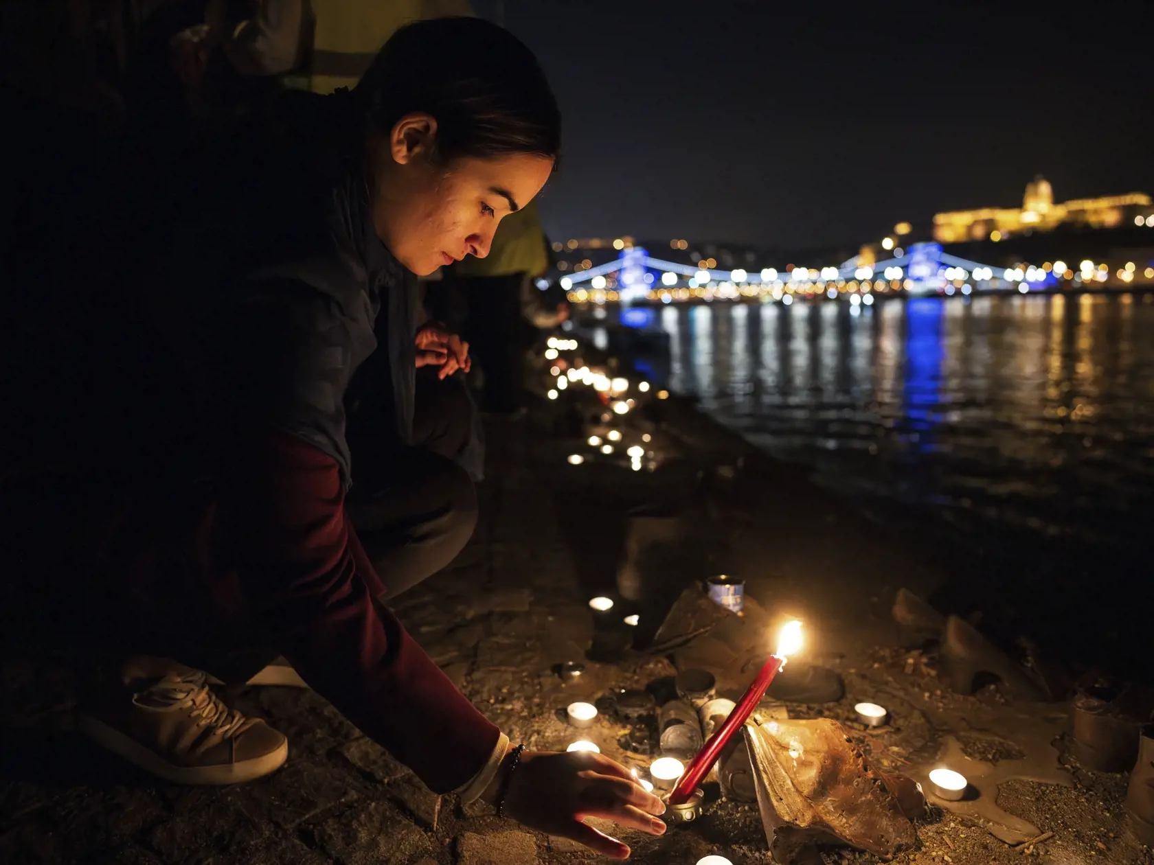 KK24 Budapešť - Na snímke ľudia zapaľujú sviečky pri medených topánkach na brehu Dunaja počas zhromaždenia na pamiatku obetí masívnych útokov militantov palestínskeho hmutia Hamas na Izrael 10. októbra 2023 v Budapešti. FOTO TASR/AP
People light candles by the cast iron shoes memorial, which pays tribute to the victims of totalitarian dictatorships, on the Pest embankment of the River Danube as part of a rally in memory of the victims of the Hamas attack on civilians in Budapest, Hungary, Tuesda