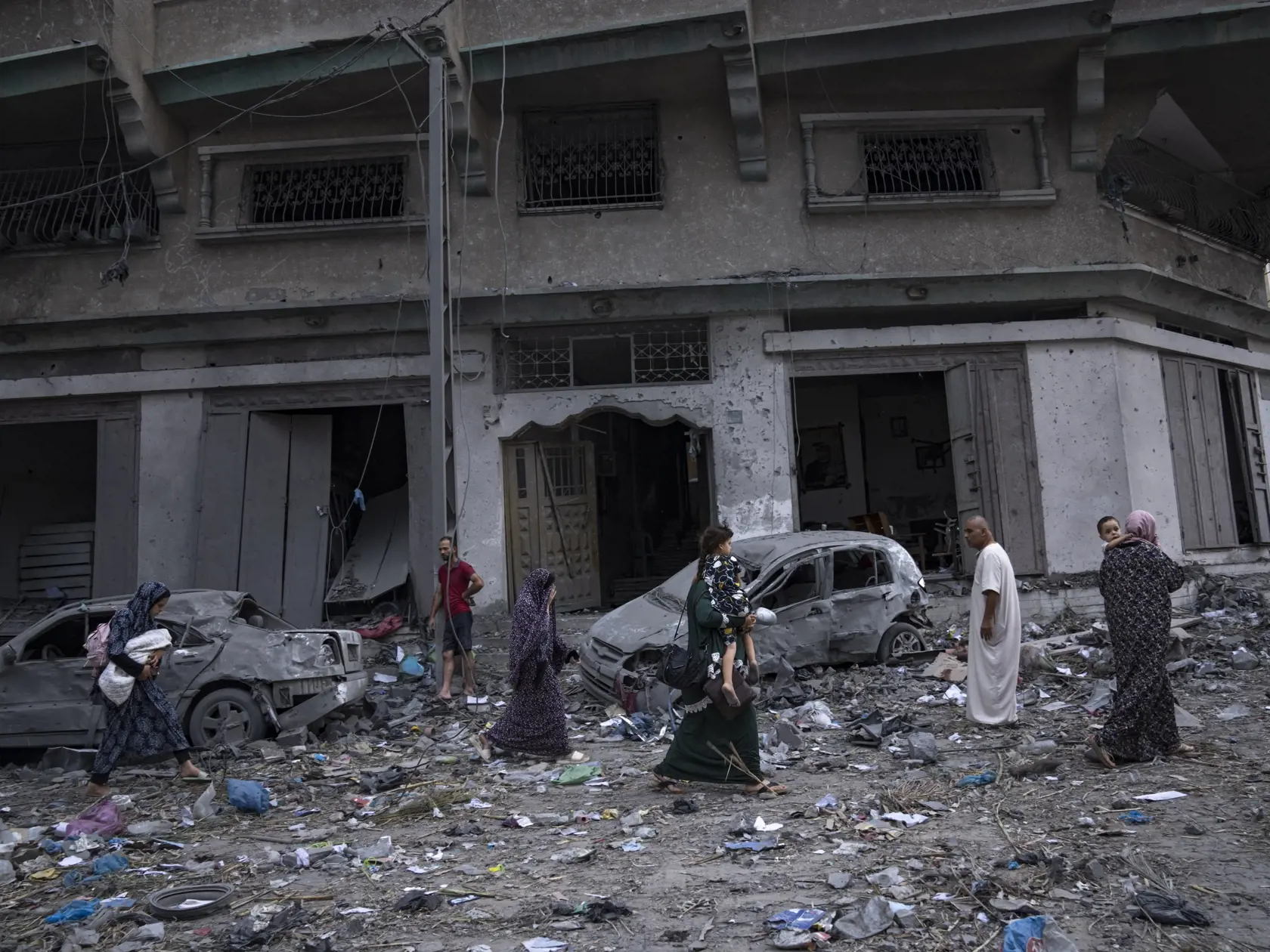 KK19 Gaza - Palestínčania kráčajú medzi ruinami po izraelských leteckých útokoch, ktoré zrovnali so zemou časť štvrte v meste Gaza, utorok 10. októbra 2023. V sobotu vpadli komandá útočníkov palestínskeho hnutia Hamas z pásma Gazy na územie Izraela, kde bezhlavo zabíjali civilistov i príslušníkov ozbrojených zložiek a brali rukojemníkov vrátane žien, detí a seniorov. Ich vpád sprevádzalo masívne ostreľovanie územia Izraela. Útok Hamasu si na území Izraela vyžiadal najmenej 900 obetí na životoch.