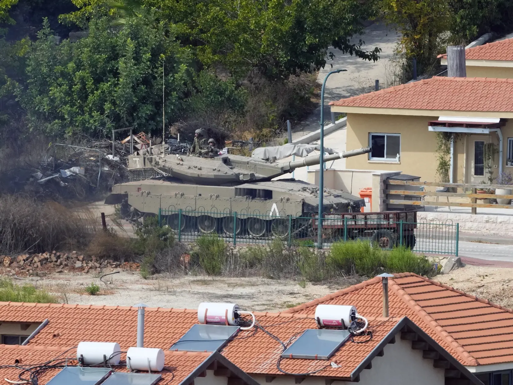KK30 Kfar Kila - Pohľad z juholibanonskej dediny Kfar Kila na izraelský tank, ktorý jadzí medzi domami v izraelskom meste Metula 9. októbra 2023. Izraelská armáda už má pod kontrolou všetky mestá, obce a ďalšie obývané lokality, do ktorých prenikli militanti z hnutia Hamas počas masívneho útoku na Izrael, uviedol v pondelok hovorca armády. Podľa neho sa tam však v okolí pásma Gazy stále môžu nachádzať palestínski ozbrojenci. FOTO TASR/AP
An Israeli tank deploys between houses in the Israeli town