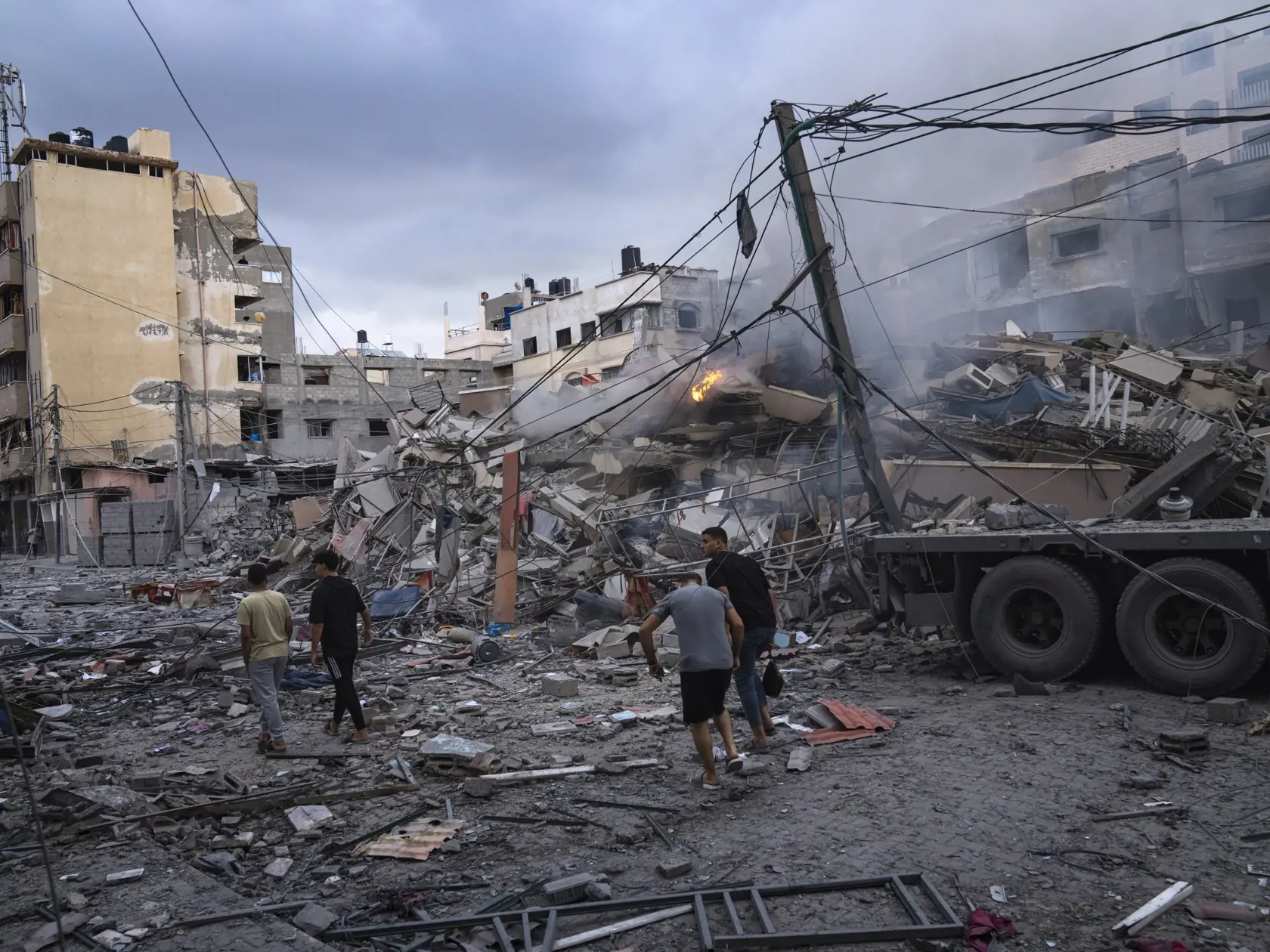 KK18 Gaza - Palestínčania kráčajú medzi ruinami po izraelských leteckých útokoch, ktoré zrovnali so zemou časť štvrte v meste Gaza, utorok 10. októbra 2023. V sobotu vpadli komandá útočníkov palestínskeho hnutia Hamas z pásma Gazy na územie Izraela, kde bezhlavo zabíjali civilistov i príslušníkov ozbrojených zložiek a brali rukojemníkov vrátane žien, detí a seniorov. Ich vpád sprevádzalo masívne ostreľovanie územia Izraela. Útok Hamasu si na území Izraela vyžiadal najmenej 900 obetí na životoch.