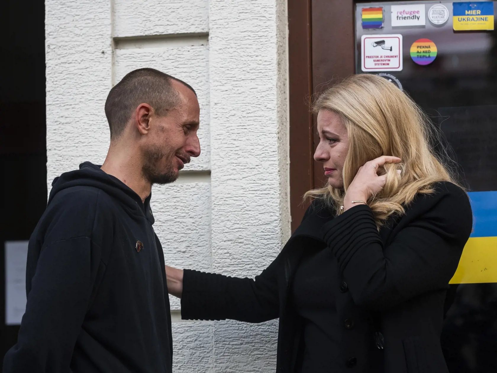 Na snímke prezidentka SR Zuzana Čaputová prišla položiť kyticu a zapáliť sviečku na miesto činu po streľbe na Zámockej ulici, vľavo ju objíma majiteľ podniku Tepláreň Roman Samotný v Bratislave 13. októbra 2022. FOTO TASR - Jaroslav Novák