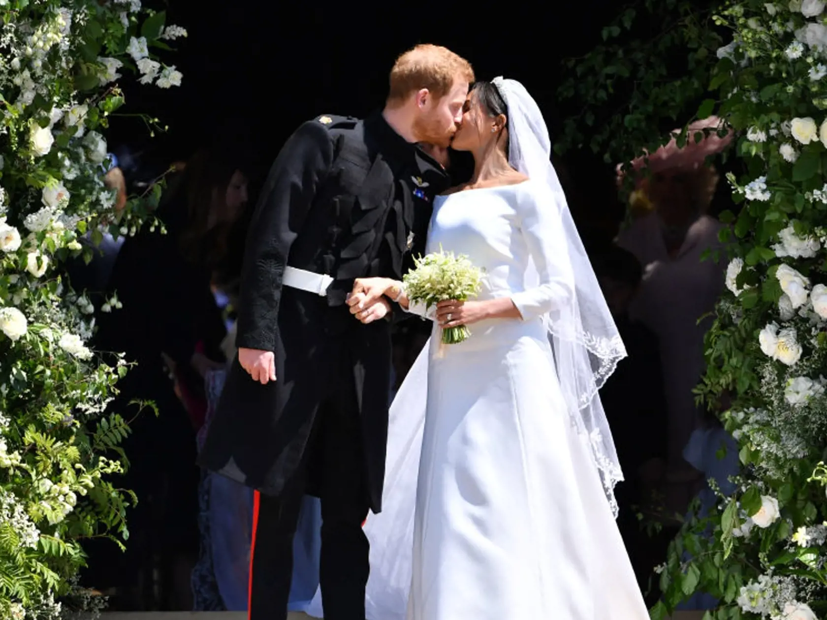 WINDSOR, UNITED KINGDOM - MAY 19: Britain's Prince Harry, Duke of Sussex kisses his wife Meghan, Duchess of Sussex as they leave from the West Door of St George's Chapel, Windsor Castle, in Windsor on May 19, 2018 in Windsor, England. (Photo by  Ben STANSALL - WPA Pool/Getty Images)