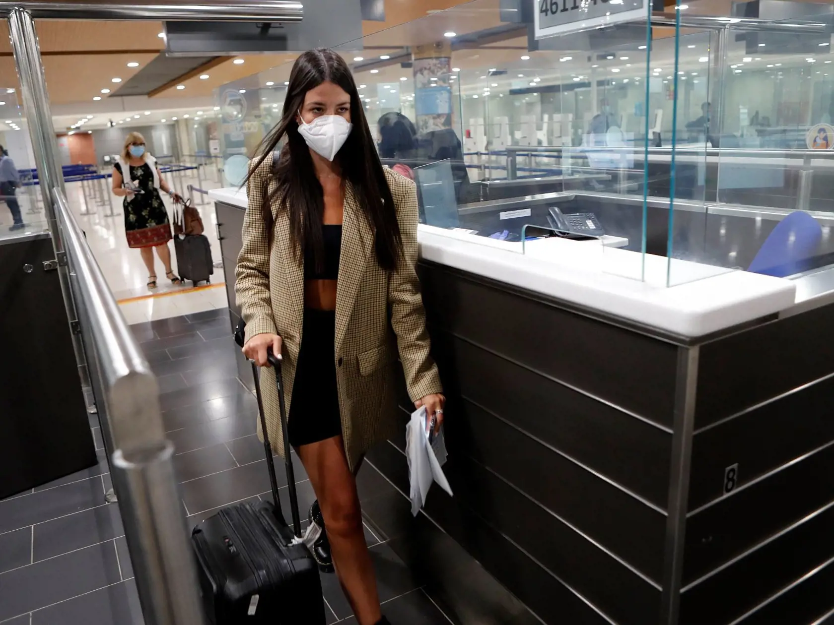 Pasažierka s ochranným rúškom na zabránenie šírenia nového koronavírusu kráča cez pasovú kontrolu po prílete na cyperské letisko v Larnake