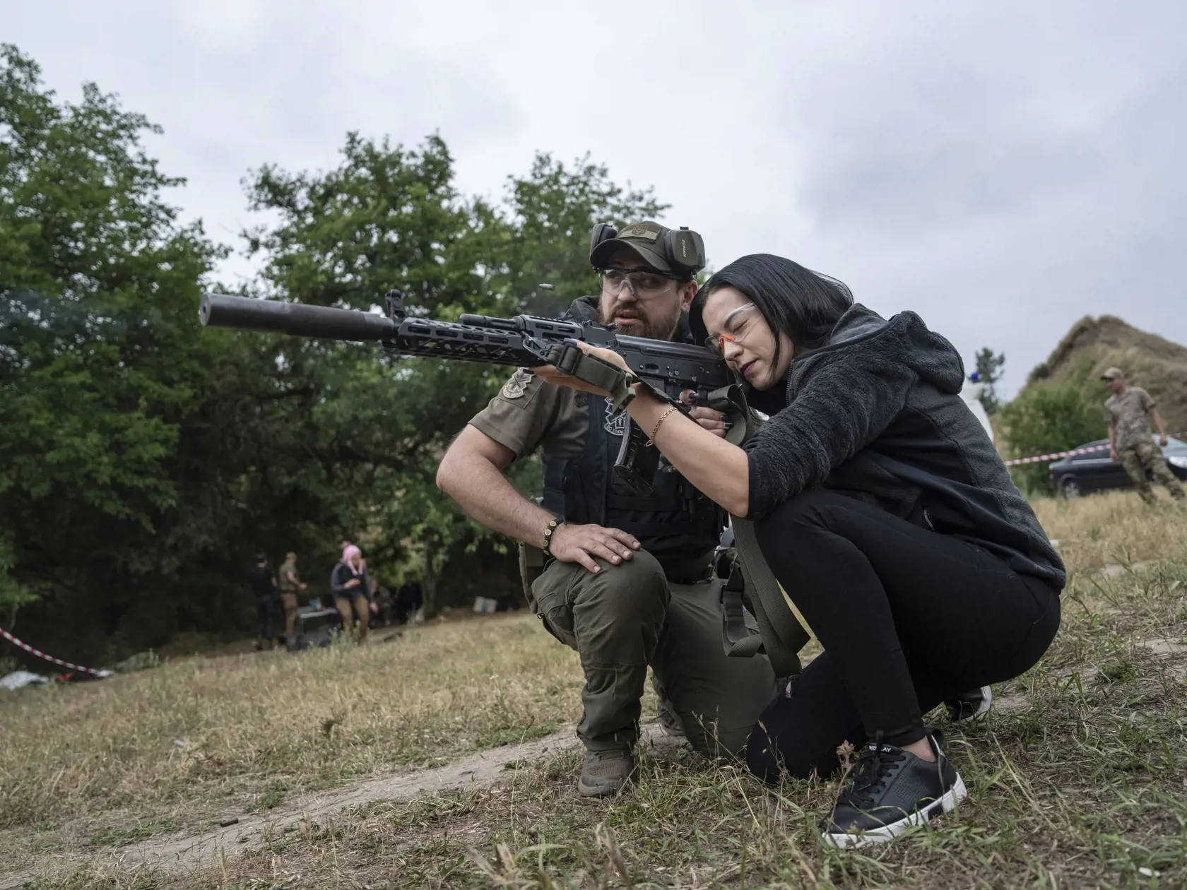 Žena strieľa z útočnej pušky AK-47 počas taktického výcviku civilistov pri priemyselnom meste Záporožie na juhovýchode Ukrajiny v nedeľu 9. júla 2023.