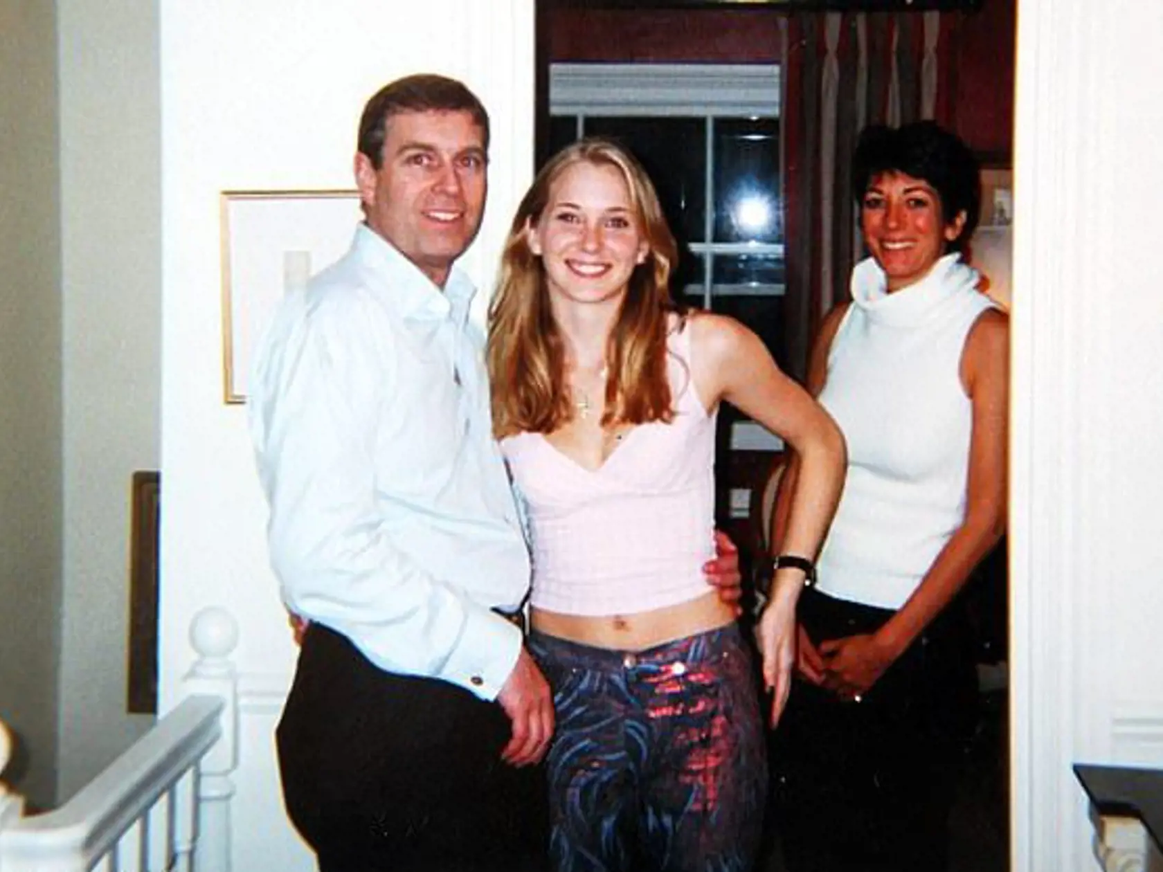 Princ Andrew a jeho údajná obeť sexuálneho zneužitia, Virginia. Vpravo sa na kameru usmieva Epsteinova pravá ruka Ghislaine Maxwell, ktorá tvrdí, že fotografia je falošná.