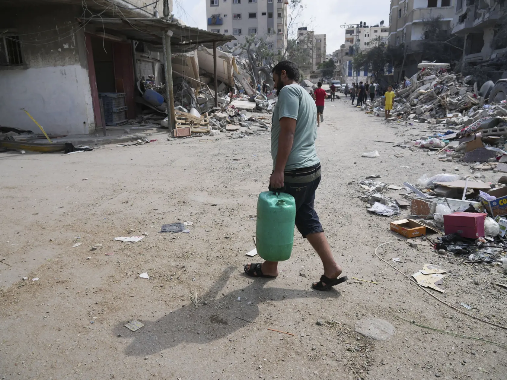 WA 29 utečenecký tábor Nuseirat - Palestínčan kráča s bandaskou vody okolo trosiek budov zničených po izraelskom raketovom útoku v utečeneckom tábore Nuseirat, ktorý je jedným z ôsmich utečeneckých táborov v pásme Gazy v pondelok 16. októbra 2023. Izraelská armáda leteckými útokmi reagovala na bezprecedentný útok palestínskeho hnutia Hamas. V sobotu 7. októbra z pásma Gazy na Izrael odpálil tisíce rakiet a stovky jeho bojovníkov prekonali zátarasy na hraniciach. V dôsledku útokov zahynulo v Izra
