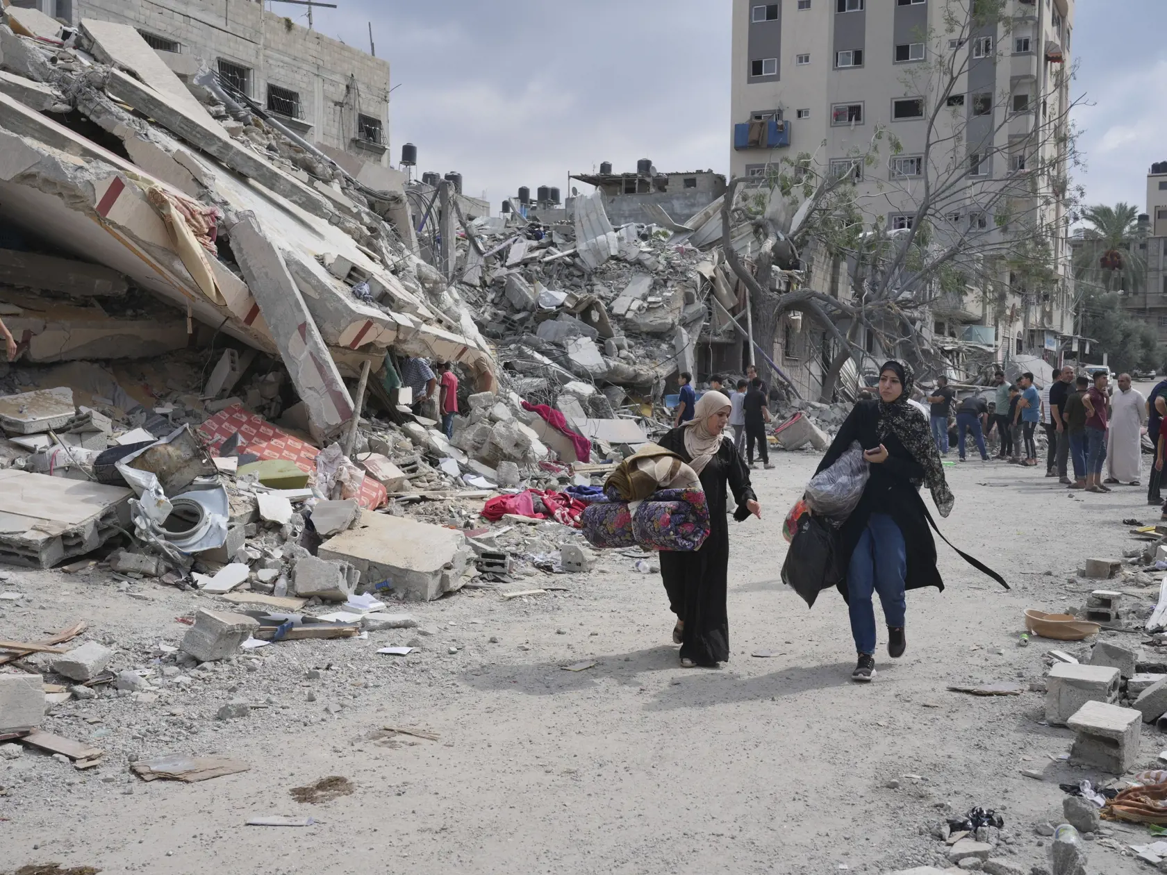 WA 30 utečenecký tábor Nuseirat - Palestínčanky kráčajú okolo trosiek budov zničených po izraelskom raketovom útoku v utečeneckom tábore Nuseirat, ktorý je jedným z ôsmich utečeneckých táborov v pásme Gazy v pondelok 16. októbra 2023. Izraelská armáda leteckými útokmi reagovala na bezprecedentný útok palestínskeho hnutia Hamas. V sobotu 7. októbra z pásma Gazy na Izrael odpálil tisíce rakiet a stovky jeho bojovníkov prekonali zátarasy na hraniciach. V dôsledku útokov zahynulo v Izraeli už vyše 1