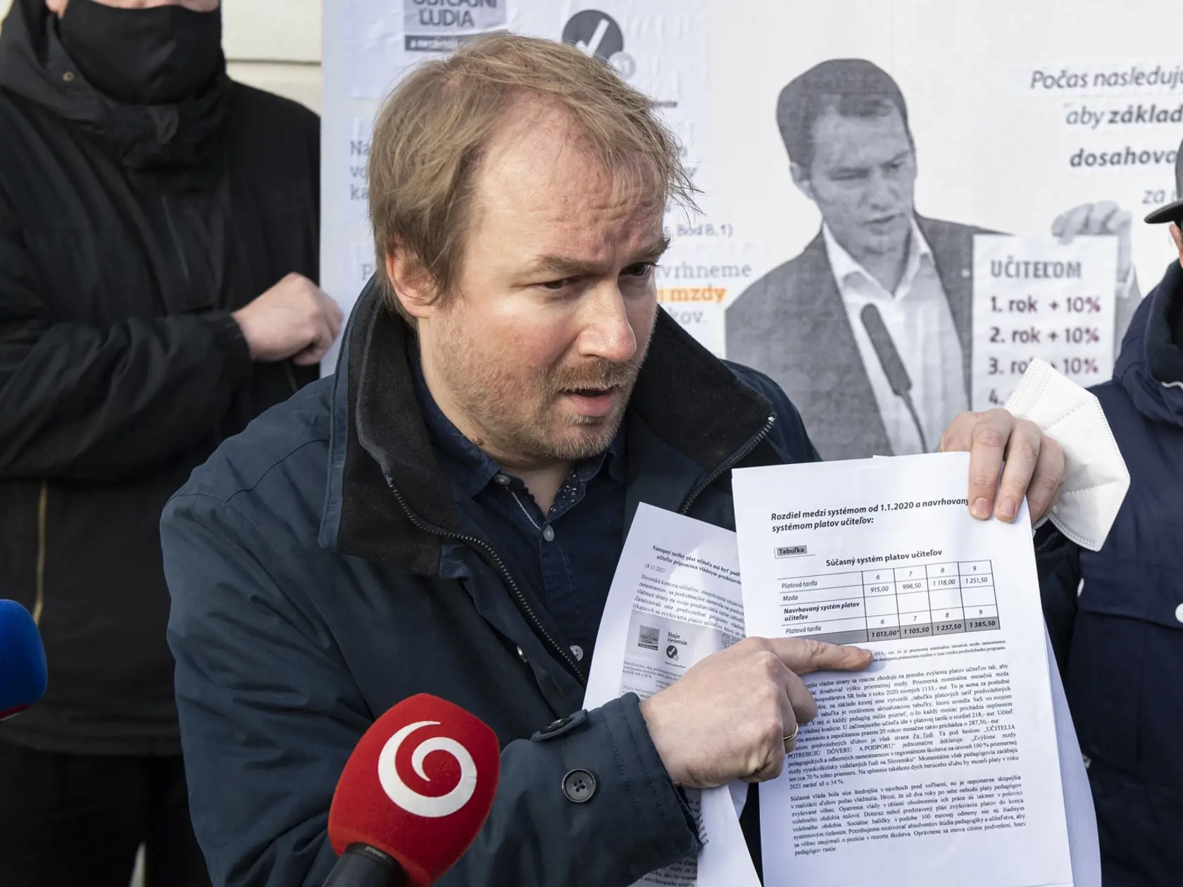 Na snímke prezident Slovenskej komory učiteľov (SKU) Vladimír Crmoman (uprostred) počas protestu pred budovou Úradu vlády SR v súvislosti so sľubovaným zvyšovaním platov učiteľom v Bratislave vo štvrtok 18. novembra 2021. Zástupcovia SKU prezentovali výsledky analýzy predvolebných programov vládnej štvorky a predstavia, ako by vyzerali platy pedagógov, keby boli tieto programy naplnené.