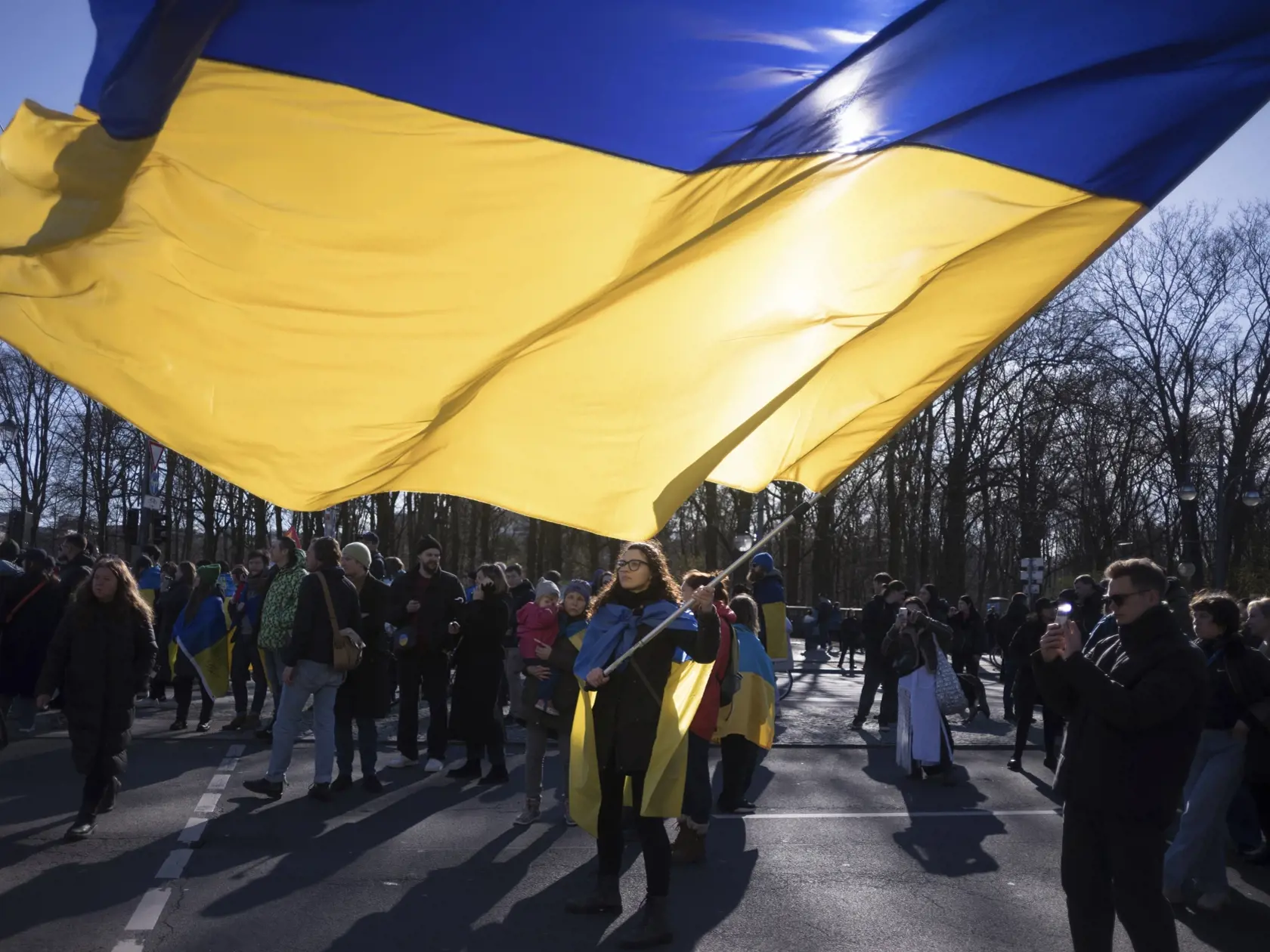Žena máva obrovskou ukrajinskou zástavou počas protestu pri príležitosti druhého výročia invázie ruských síl na Ukrajinu pri Brandenburskej bráne v Berlíne 24. februára 2024.