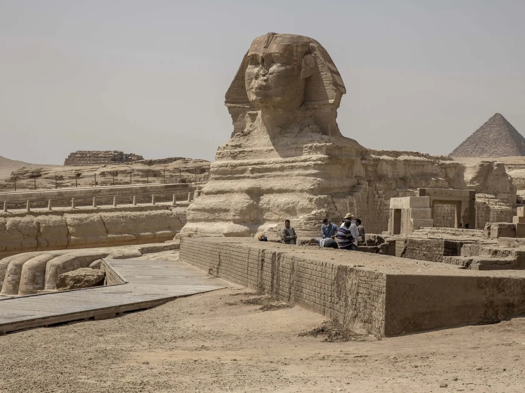 Ľudia pracujú vedľa sochy Sfingy a pyramíd v Gíze v Egypte. Egypt oznámil, že zavedie nočný zákaz vychádzania v snahe spomaliť šírenie nového koronavírusu.