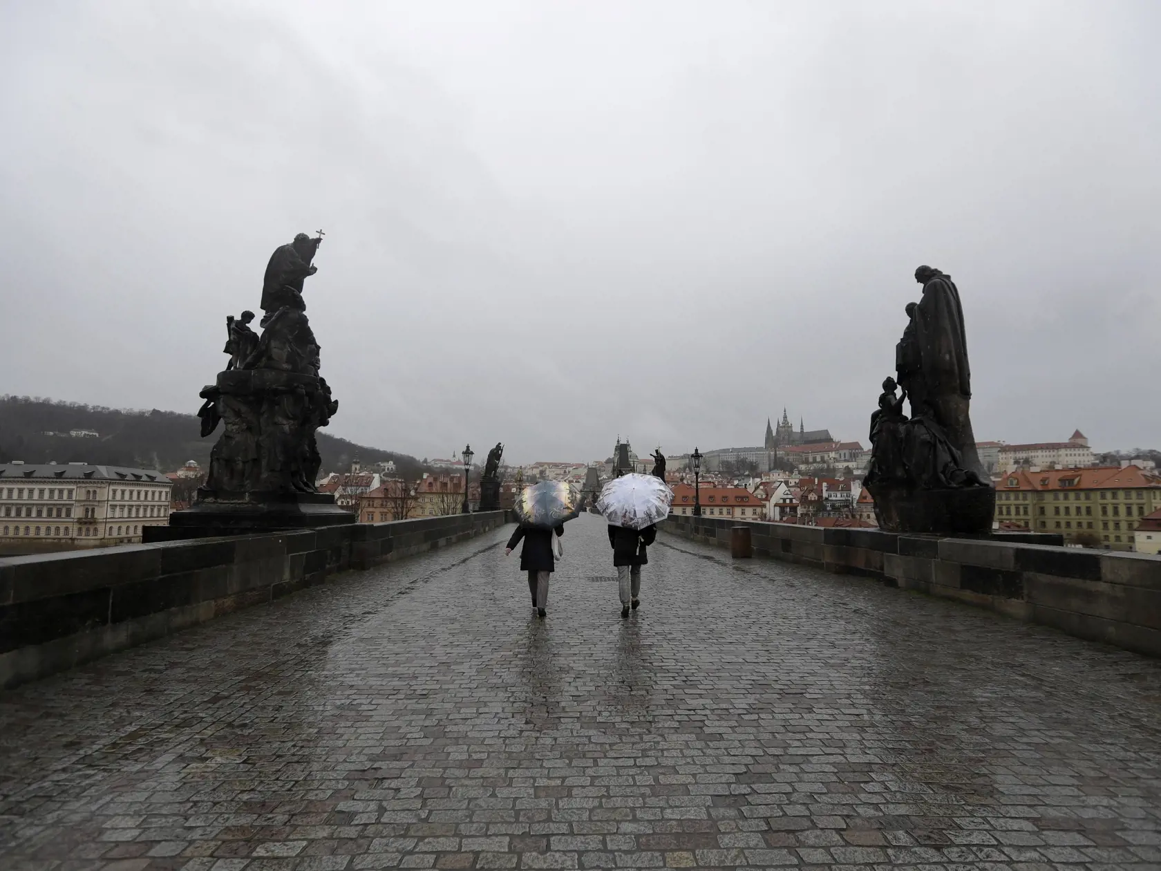 KK19 Praha - Ľudia kráčajú po prázdnom Karlovom moste 11. marca 2020 v Prahe. V Českej republike momentálne evidujú už 67 prípadov nákazy koronavírusom SARS-CoV-2. O troch nových prípadoch informoval v stredu minister zdravotníctva Adam Vojtěch.  Česko v utorok zakázalo podujatia s viac ako 100 účastníkmi. Týka sa to divadelných, hudobných a filmových predstavení, ako aj športových či náboženských udalostí. FOTO TASR/AP
People walk across an unusually empty medieval Charles Bridge in Prague, Cze