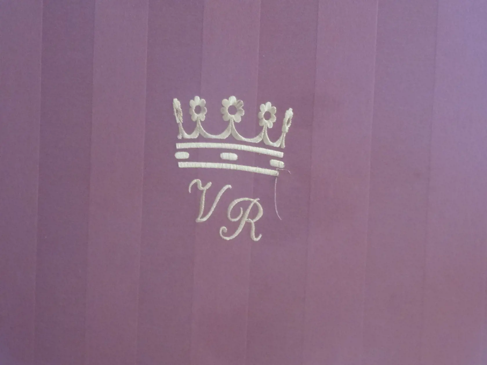 Na záhlaví postele je kráľovská korunka a monogram jeho a partnerky.