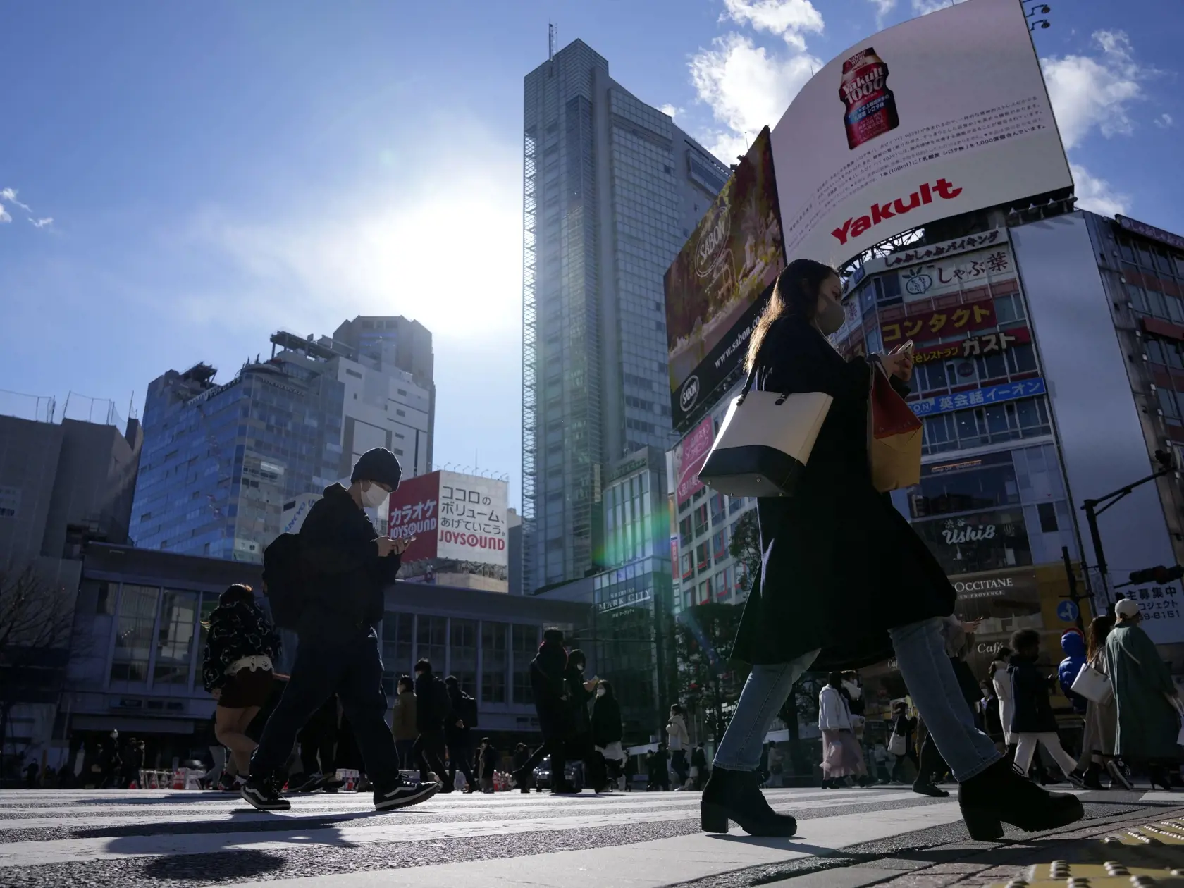 Ľudia s ochrannými rúškami kráčajú cez križovatku v Tokiu 21. januára 2022. Japonská vláda schválila v stredu nové obmedzenia proti koronavírusu pre veľkú časť krajiny vrátane hlavného mesta Tokio. Snaží sa tak bojovať proti rekordnému počtu prípadov nákazy, pripisovanému variantu omikron.