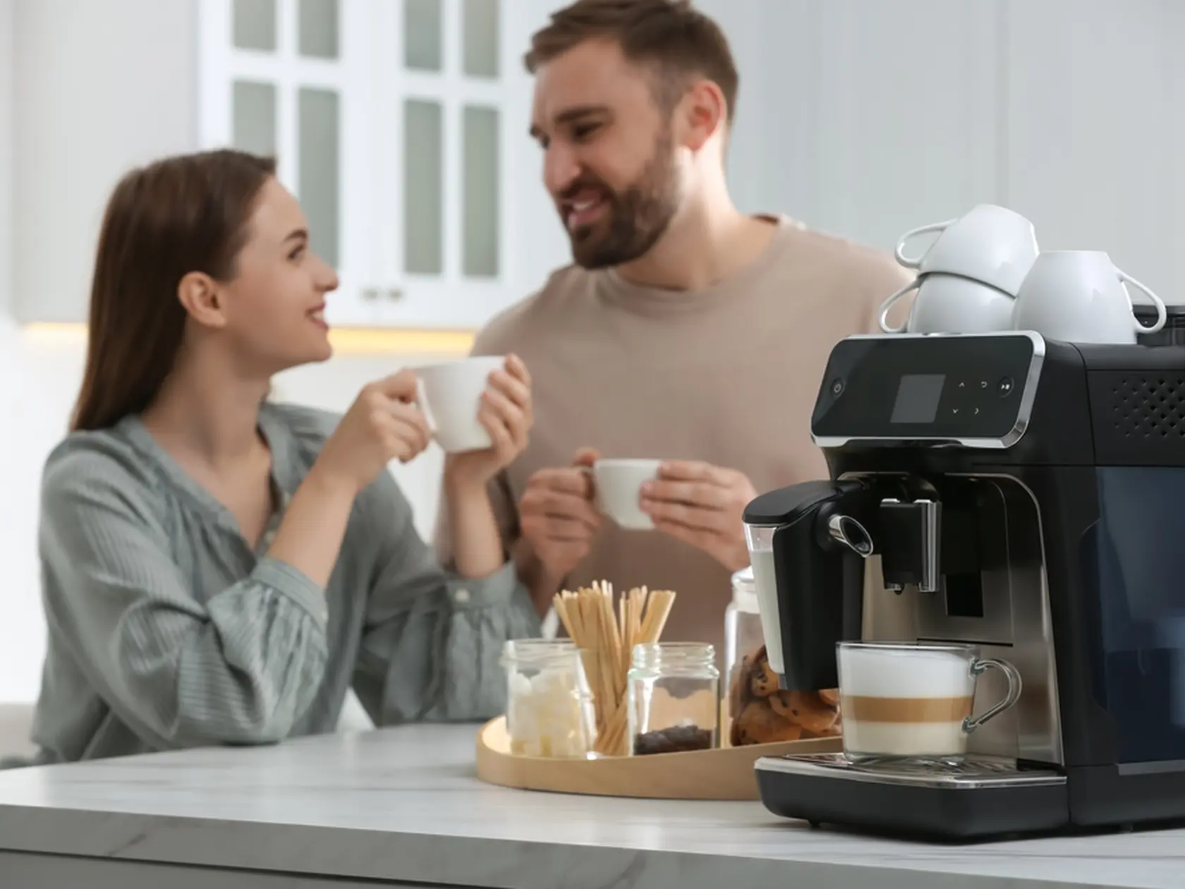 Happy couple enjoying fresh aromatic coffee in kitchen, focus on modern machine
