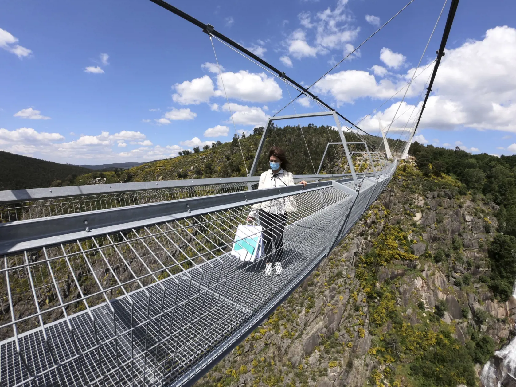 WA 24 Arouca - Žena kráča po najdlhšom visutom moste pre peších na svete, ktorý sa nachádza v meste Arouca na severe Portugalska v nedeľu 2. mája 2021. Most Arauca, ktorý slávnostne otvorili v nedeľu, má dĺžku 516 metrov  a nachádza sa 175 metrov nad riekou Paiva. Ponúka panoramatické výhľady na vodopád, roklinu, ale aj spomínanú rieku Paiva. FOTO TASR/AP 

A woman walks across a narrow footbridge suspended across a river canyon, which claims to be the world's longest pedestrian bridge, in Arouc