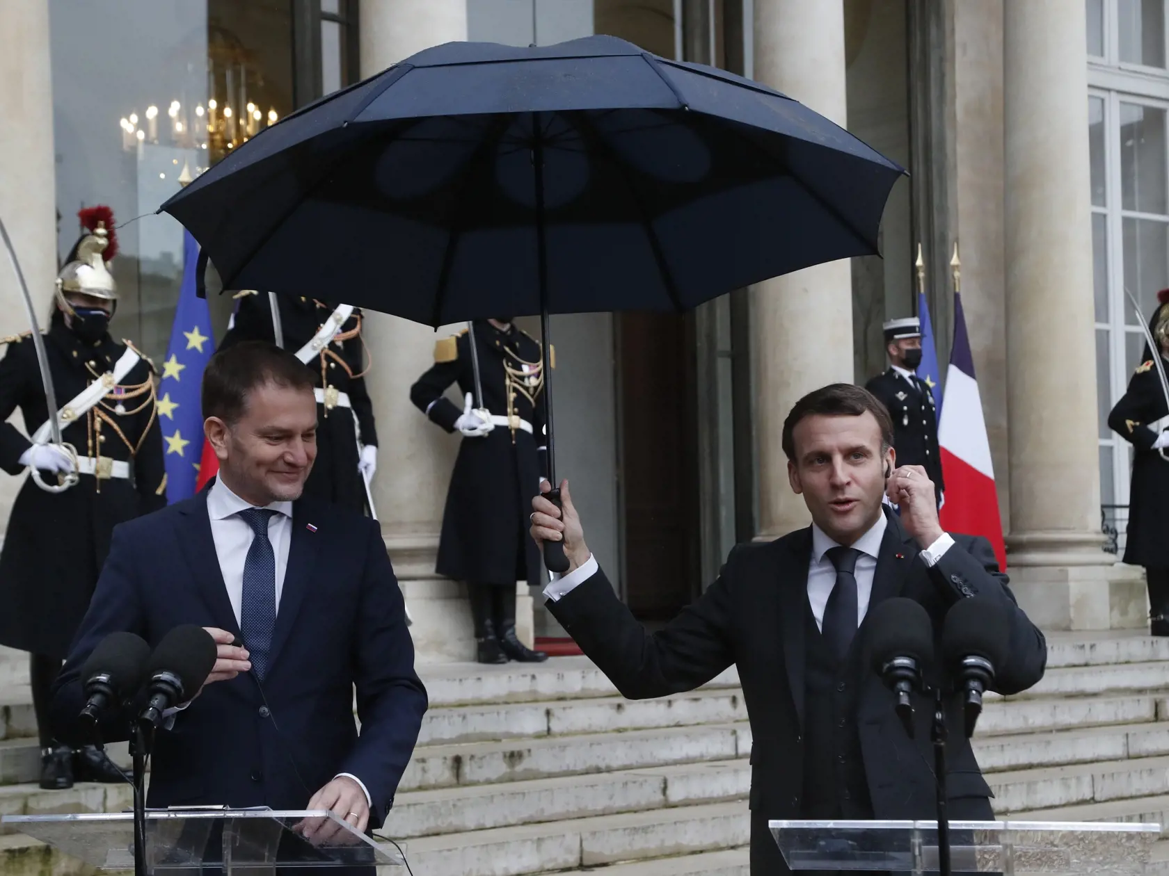 Francúzsky prezident Emmanuel Macron (vpravo) drží dáždnik nad slovenským expremiérom Igorom Matovičom počas vyhlásenia pred spoločným rokovaním 3. februára 2021 v Elyzejskom paláci v Paríži.
French President Emmanuel Macron, right, holds an umbrella as he and Slovakia's Prime Minister Igor Matovic address reporters before a working lunch at the Elysee Palace Wednesday, Feb. 3, 2021 in Paris. (AP Photo/Thibault Camus)